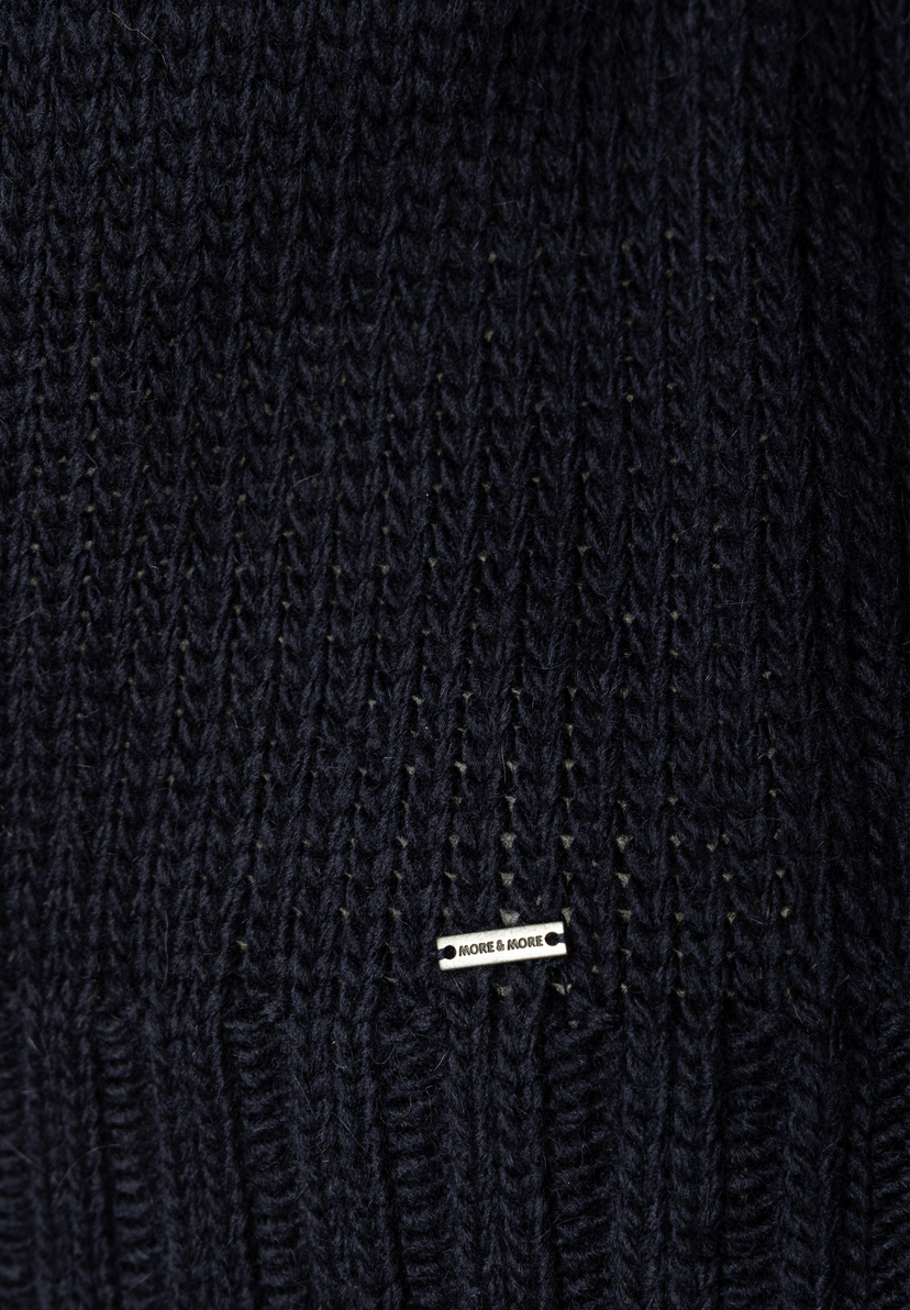 MORE & MORE Pullover: Detailaufnahme des dunkelblauen Strickmusters mit eingearbeitetem silbernen Markenlogo. MORE & MORE Pullover: Detailaufnahme des dunkelblauen Strickmusters mit eingearbeitetem silbernen Markenlogo.