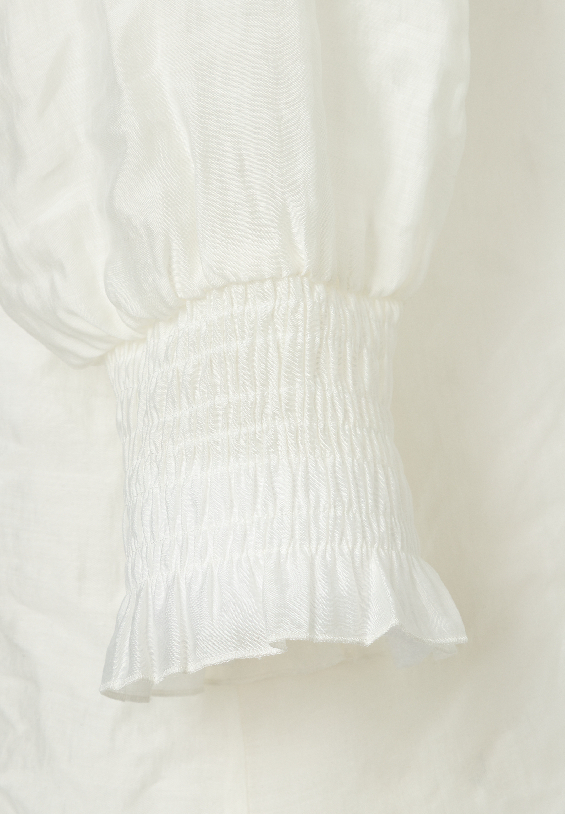 Detailaufnahme der gerafften Manschette einer weißen MORE & MORE Bluse mit Rüschenabschluss. Detailaufnahme der gerafften Manschette einer weißen MORE & MORE Bluse mit Rüschenabschluss.