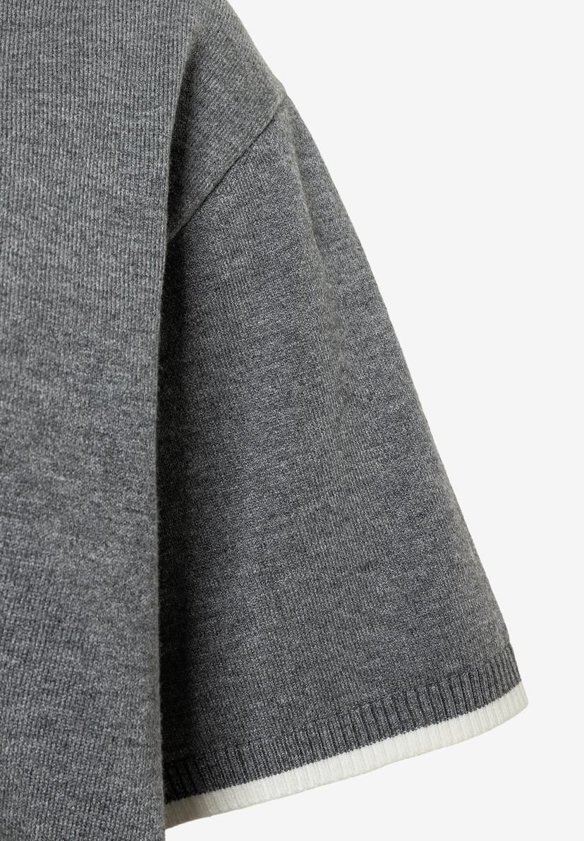 Nahaufnahme eines grauen MORE & MORE Feinstrick-Pullovers mit kurzem Ärmel und weißem Saum. Nahaufnahme eines grauen MORE & MORE Feinstrick-Pullovers mit kurzem Ärmel und weißem Saum.