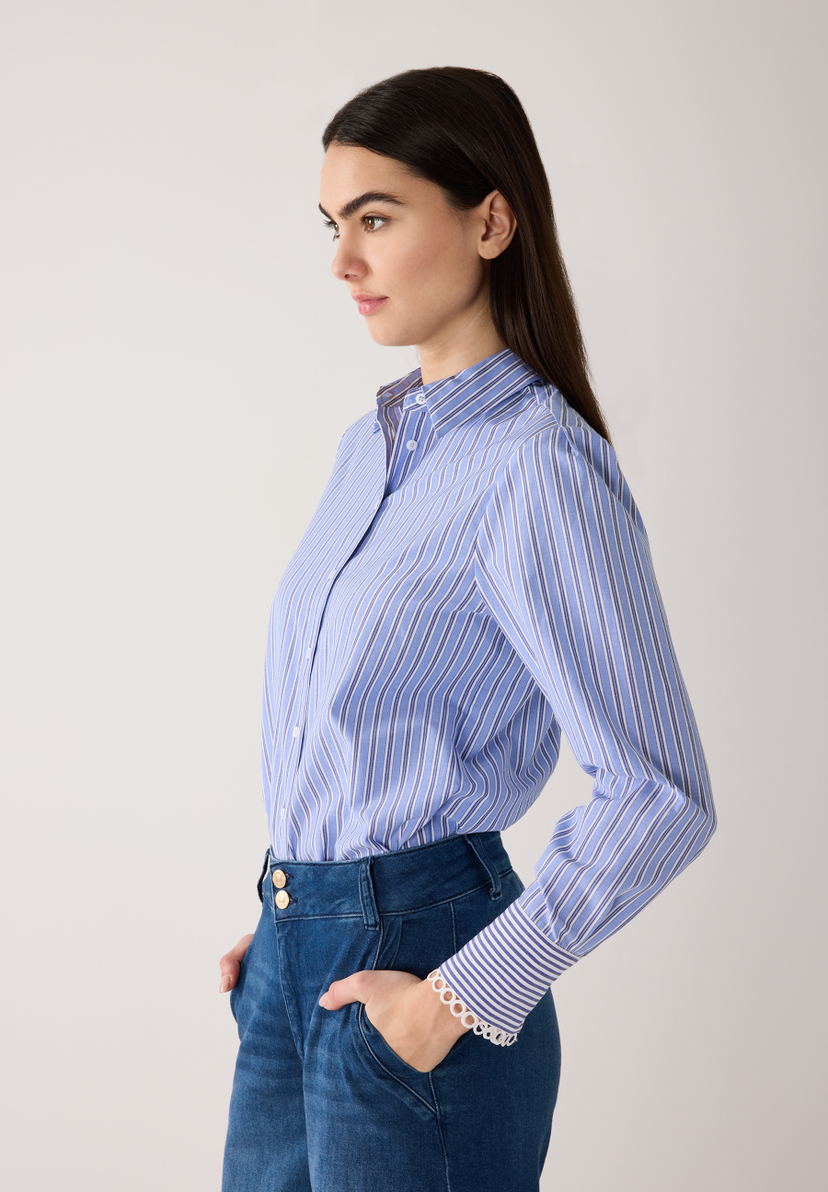 Eine Frau trägt eine gestreifte Popeline-Bluse von MORE & MORE und blaue Jeans, posiert im Studio. Eine Frau trägt eine gestreifte Popeline-Bluse von MORE & MORE und blaue Jeans, posiert im Studio.
