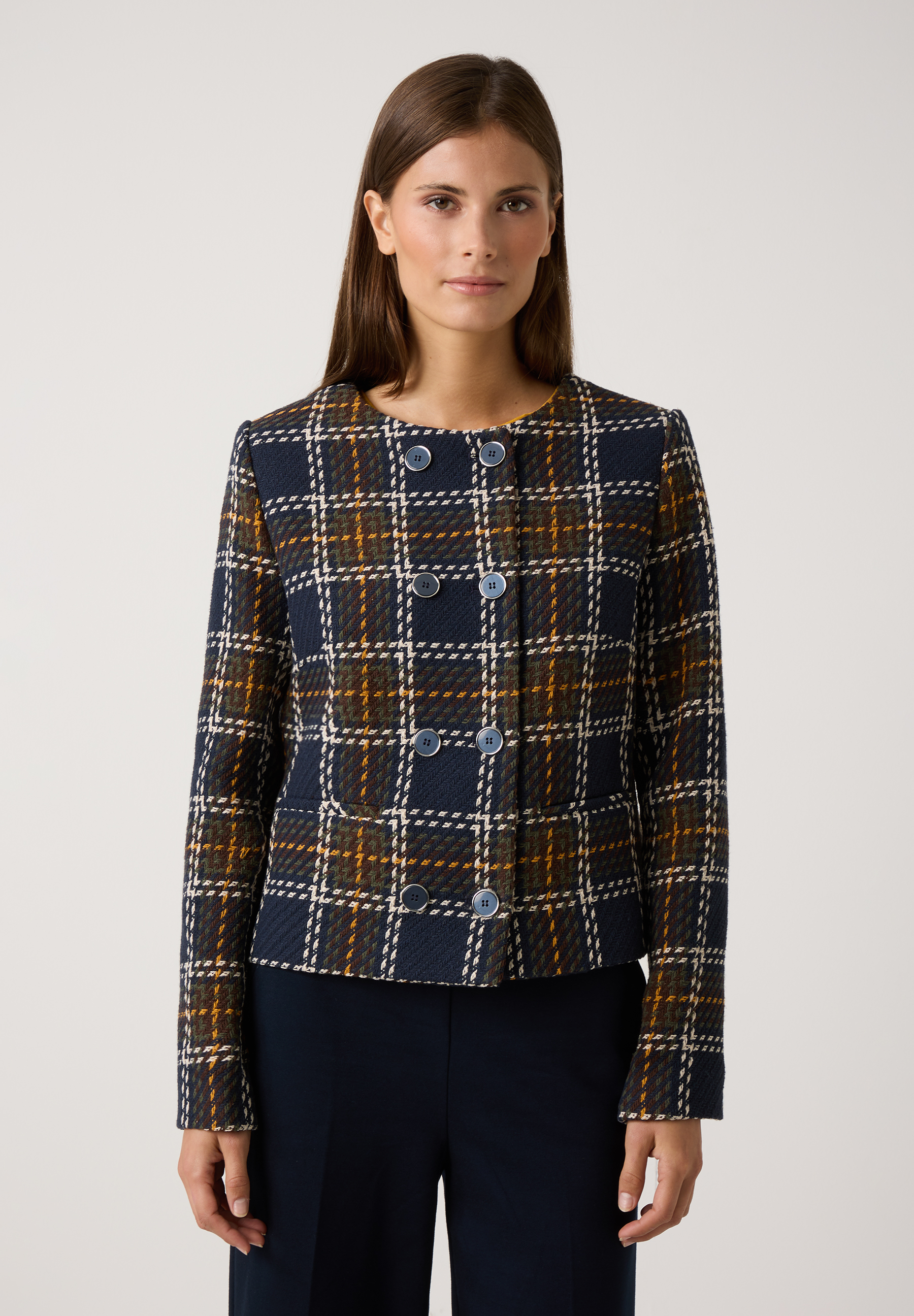 Eine Frau trägt einen MORE & MORE Blazer mit Karomuster in Blau, Braun und Gelb vor einem weißen Hintergrund. Eine Frau trägt einen MORE & MORE Blazer mit Karomuster in Blau, Braun und Gelb vor einem weißen Hintergrund.
