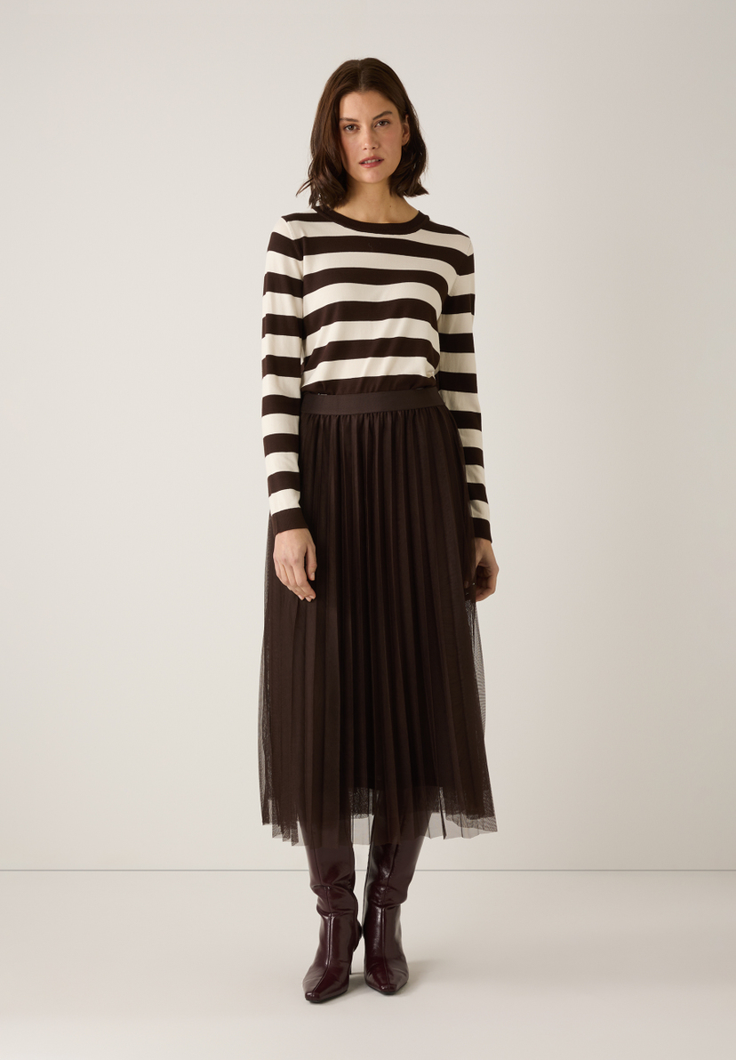 Eine Frau trägt einen MORE & MORE-Pullover mit braunen und weißen Streifen, einen Rock und Stiefel. Eine Frau trägt einen MORE & MORE-Pullover mit braunen und weißen Streifen, einen Rock und Stiefel.