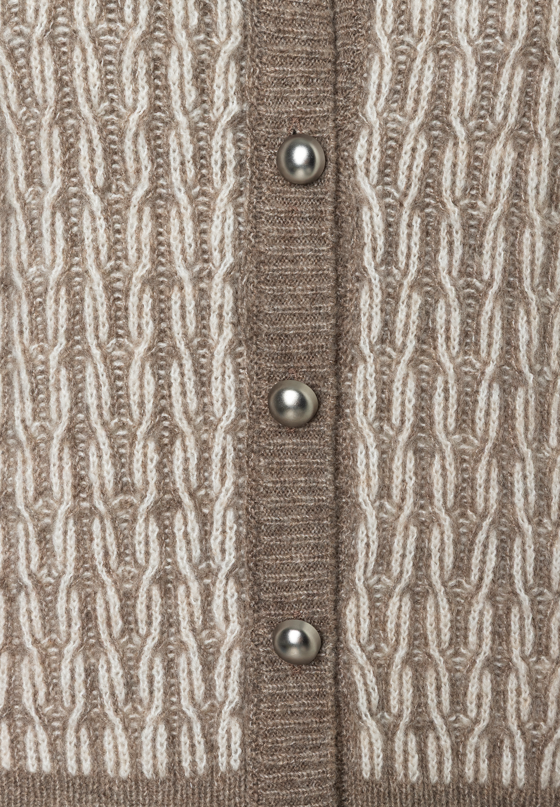 Nahaufnahme einer MORE & MORE Strickjacke mit Zopfmuster und silbernen Knöpfen. Das Material wirkt wärmend und hat einen weichen Griff. Nahaufnahme einer MORE & MORE Strickjacke mit Zopfmuster und silbernen Knöpfen. Das Material wirkt wärmend und hat einen weichen Griff.