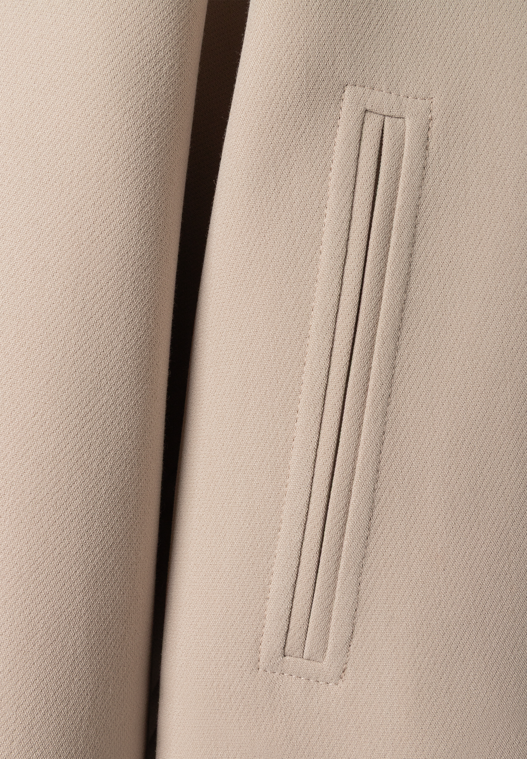 Detailansicht des MORE & MORE Blazers: Eine eckige Pattentasche mit vertikalen Ziernähten ist auf dem beigen Stoff zu sehen. Detailansicht des MORE & MORE Blazers: Eine eckige Pattentasche mit vertikalen Ziernähten ist auf dem beigen Stoff zu sehen.