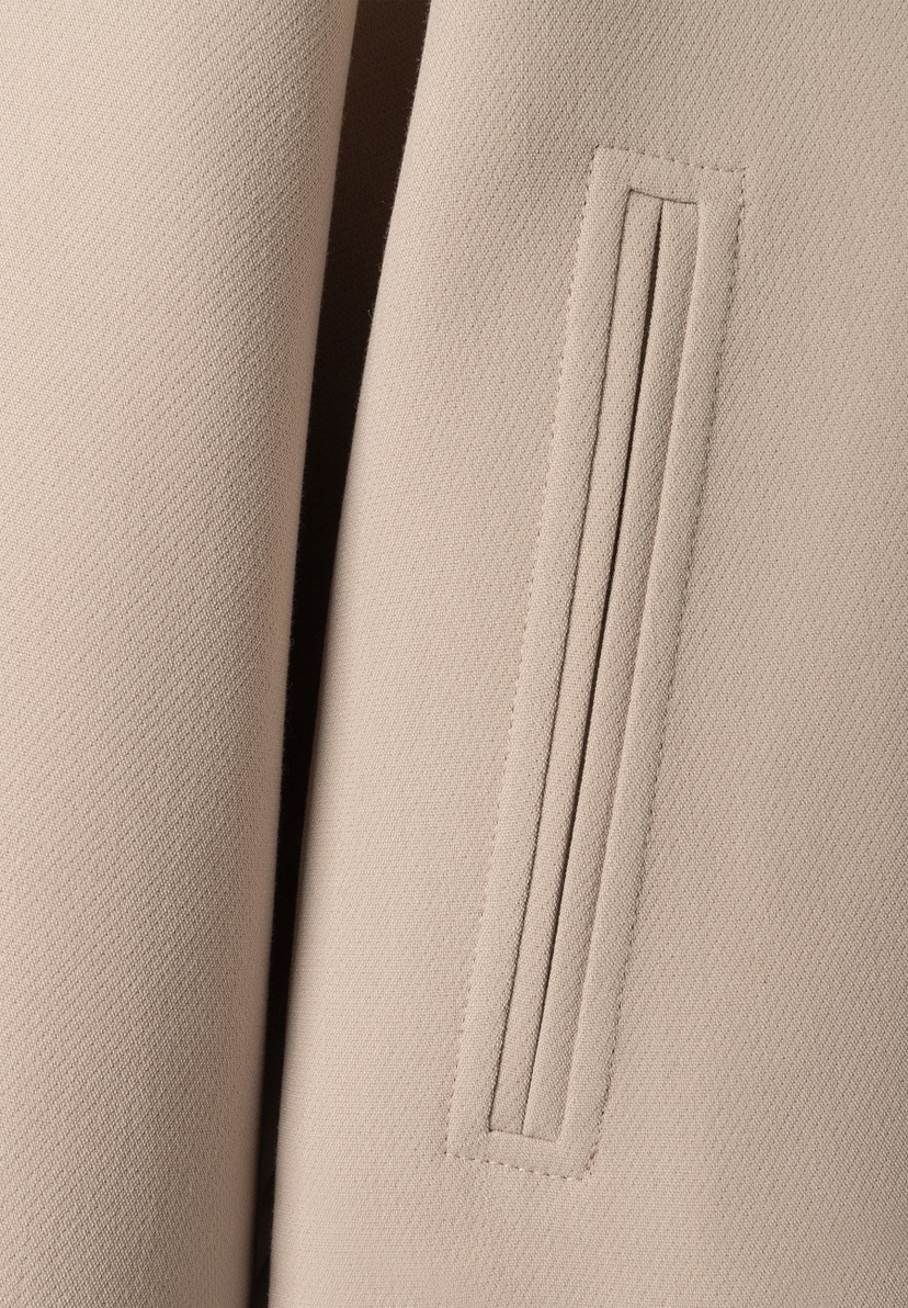 Detailansicht des MORE & MORE Blazers: Eine eckige Pattentasche mit vertikalen Ziernähten ist auf dem beigen Stoff zu sehen. Detailansicht des MORE & MORE Blazers: Eine eckige Pattentasche mit vertikalen Ziernähten ist auf dem beigen Stoff zu sehen.