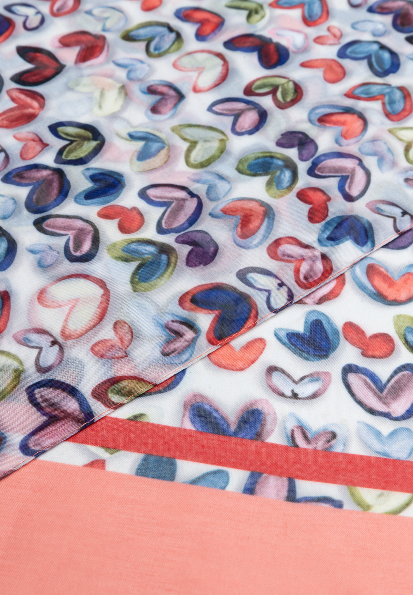 Nahaufnahme eines MORE & MORE Accessoires mit bunten Herzchen auf hellem Grund und einem korallfarbenen Stoffteil. Nahaufnahme eines MORE & MORE Accessoires mit bunten Herzchen auf hellem Grund und einem korallfarbenen Stoffteil.
