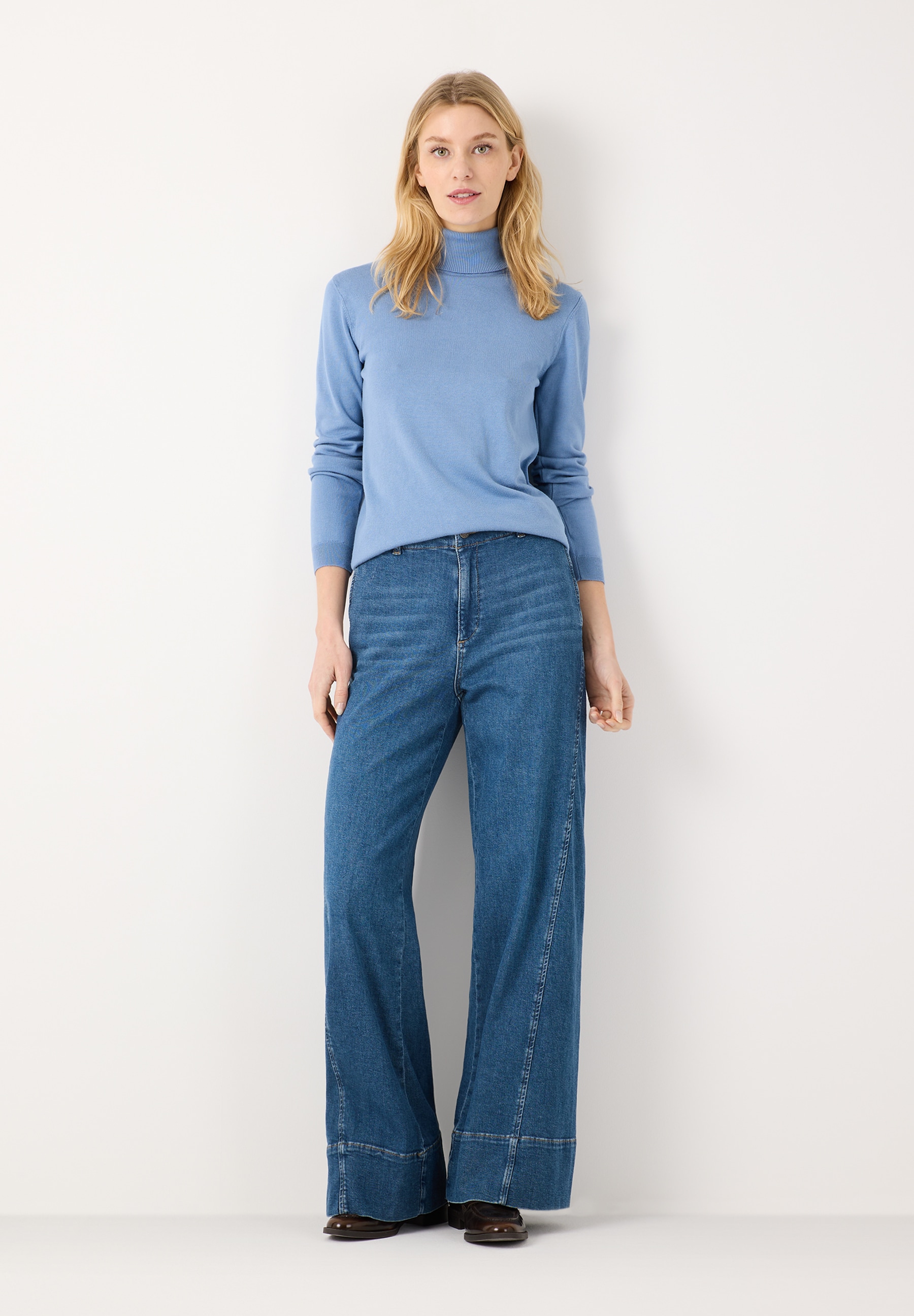 MORE & MORE Jeans: Helle Jeans mit weitem Bein und hellem Rollkragenpullover vor weißem Hintergrund. MORE & MORE Jeans: Helle Jeans mit weitem Bein und hellem Rollkragenpullover vor weißem Hintergrund.