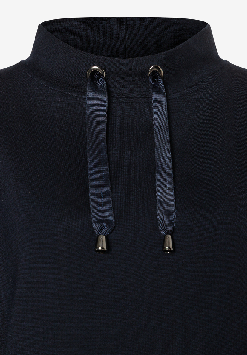 MORE & MORE dunkelblauer Sweatshirt mit hohem Kragen und zwei glänzenden Metallösen, durch die Bänder mit Metallenden verlaufen. MORE & MORE dunkelblauer Sweatshirt mit hohem Kragen und zwei glänzenden Metallösen, durch die Bänder mit Metallenden verlaufen.