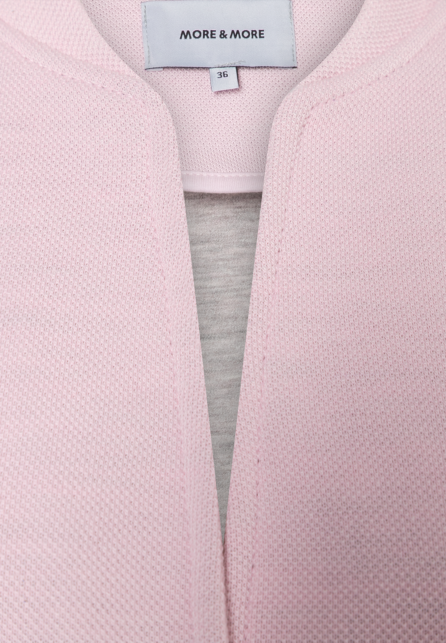 Nahaufnahme eines MORE & MORE Blazers aus Piqué-Jersey in Rosa mit Größenetikett 36. Nahaufnahme eines MORE & MORE Blazers aus Piqué-Jersey in Rosa mit Größenetikett 36.