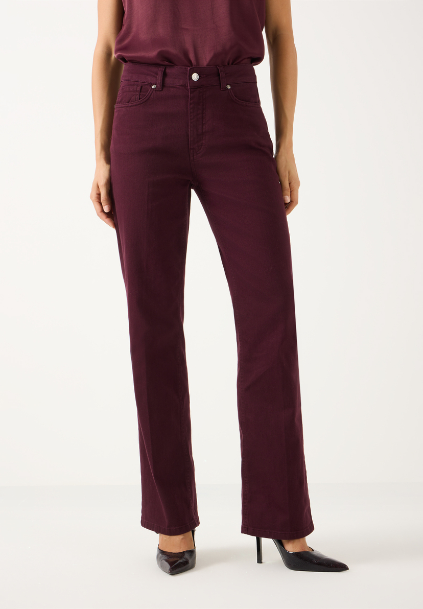 MORE & MORE Damen-Jeans in Burgunderrot. Das Model trägt eine dunkelrote Jeans mit geradem Bein und dazu passende Oberteile und spitze schwarze Absätze.