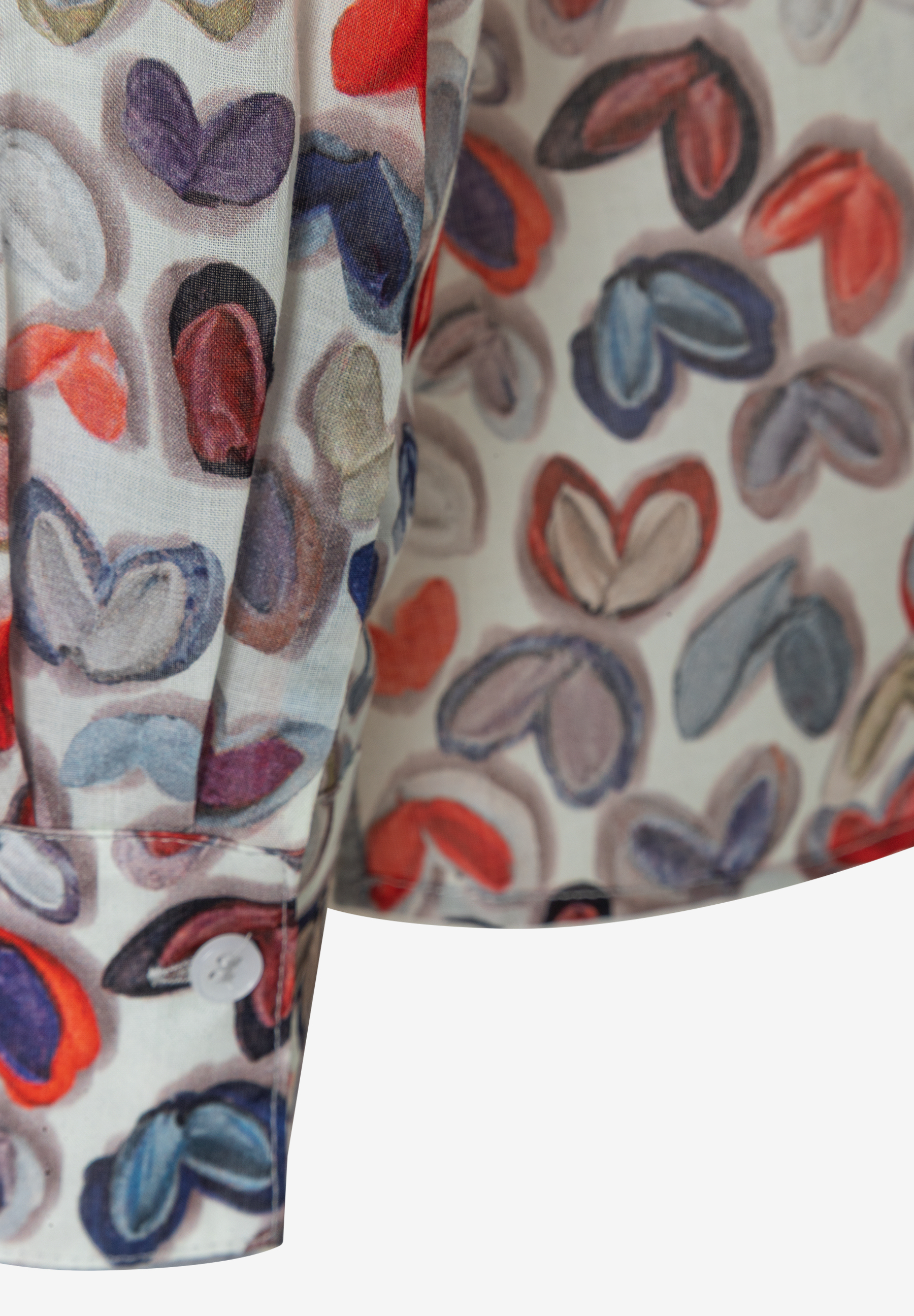 Detailansicht einer MORE & MORE Bluse mit buntem Herzmuster und Knopf am Ärmel. Detailansicht einer MORE & MORE Bluse mit buntem Herzmuster und Knopf am Ärmel.