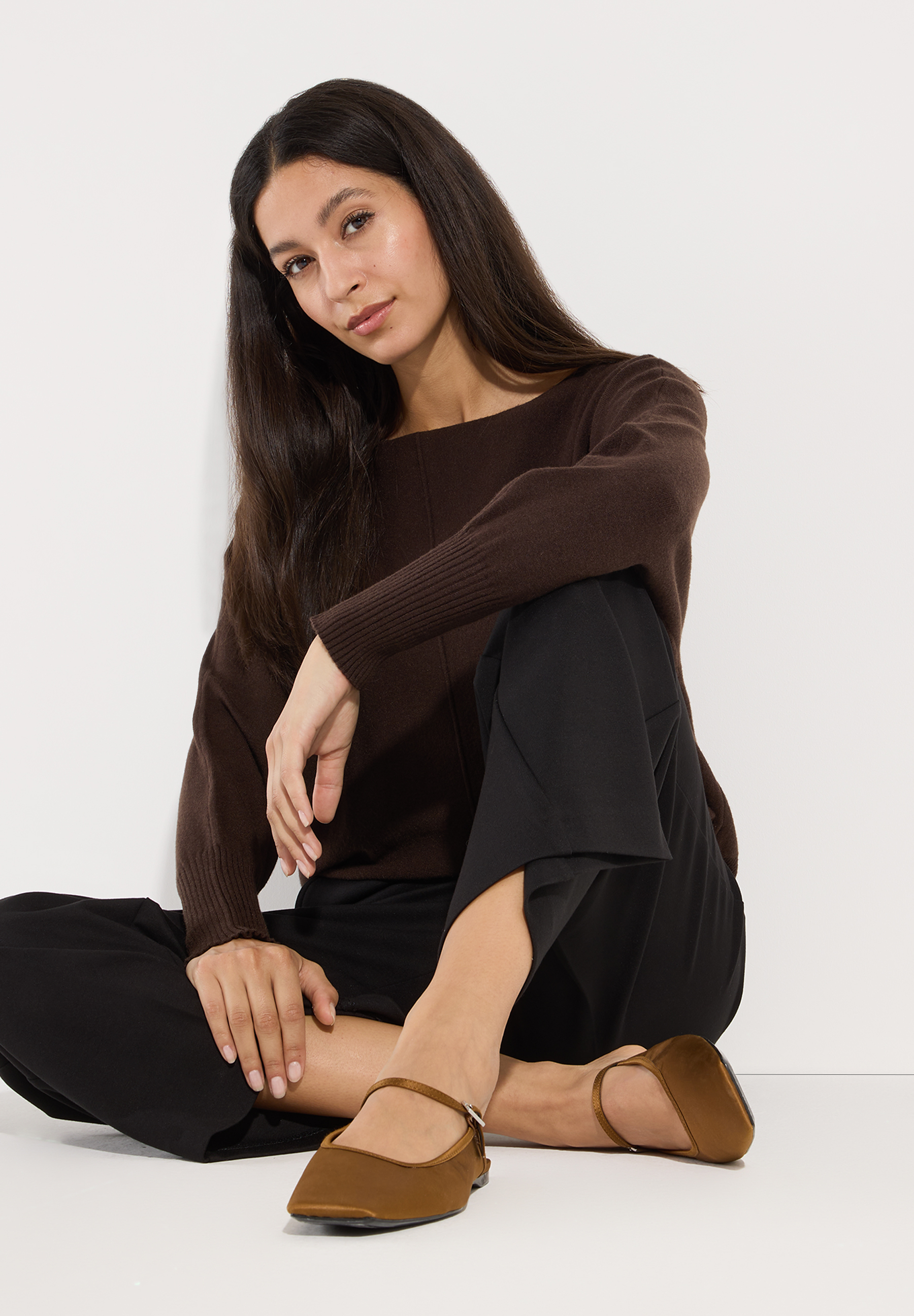 MORE & MORE dunkelbrauner Pullover & schwarze Hose, dazu flache braune Riemchensandalen, im Schneidersitz. MORE & MORE dunkelbrauner Pullover & schwarze Hose, dazu flache braune Riemchensandalen, im Schneidersitz.