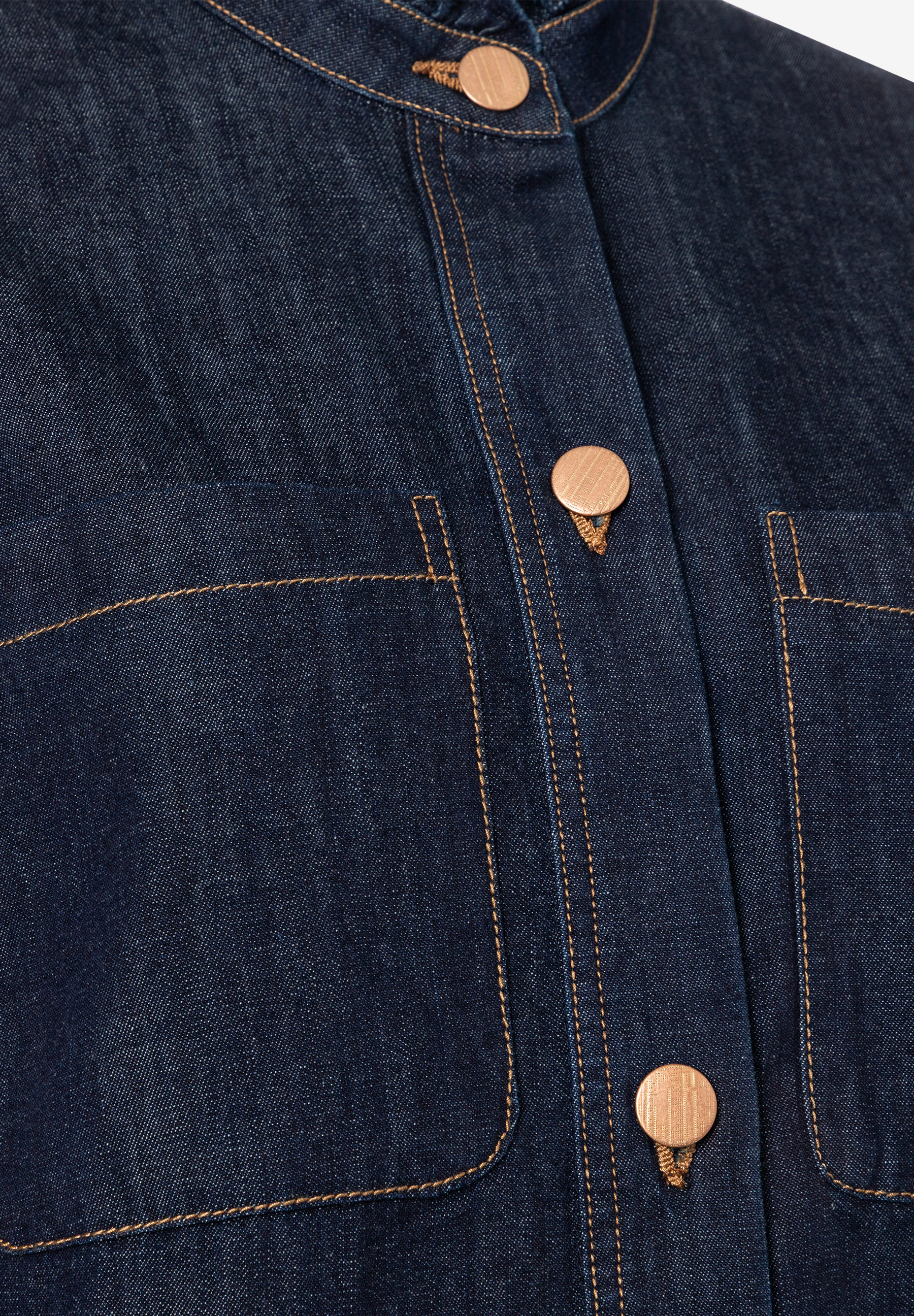 Nahaufnahme einer MORE & MORE Denim-Bluse mit Knöpfen und Taschen. Nahaufnahme einer MORE & MORE Denim-Bluse mit Knöpfen und Taschen.