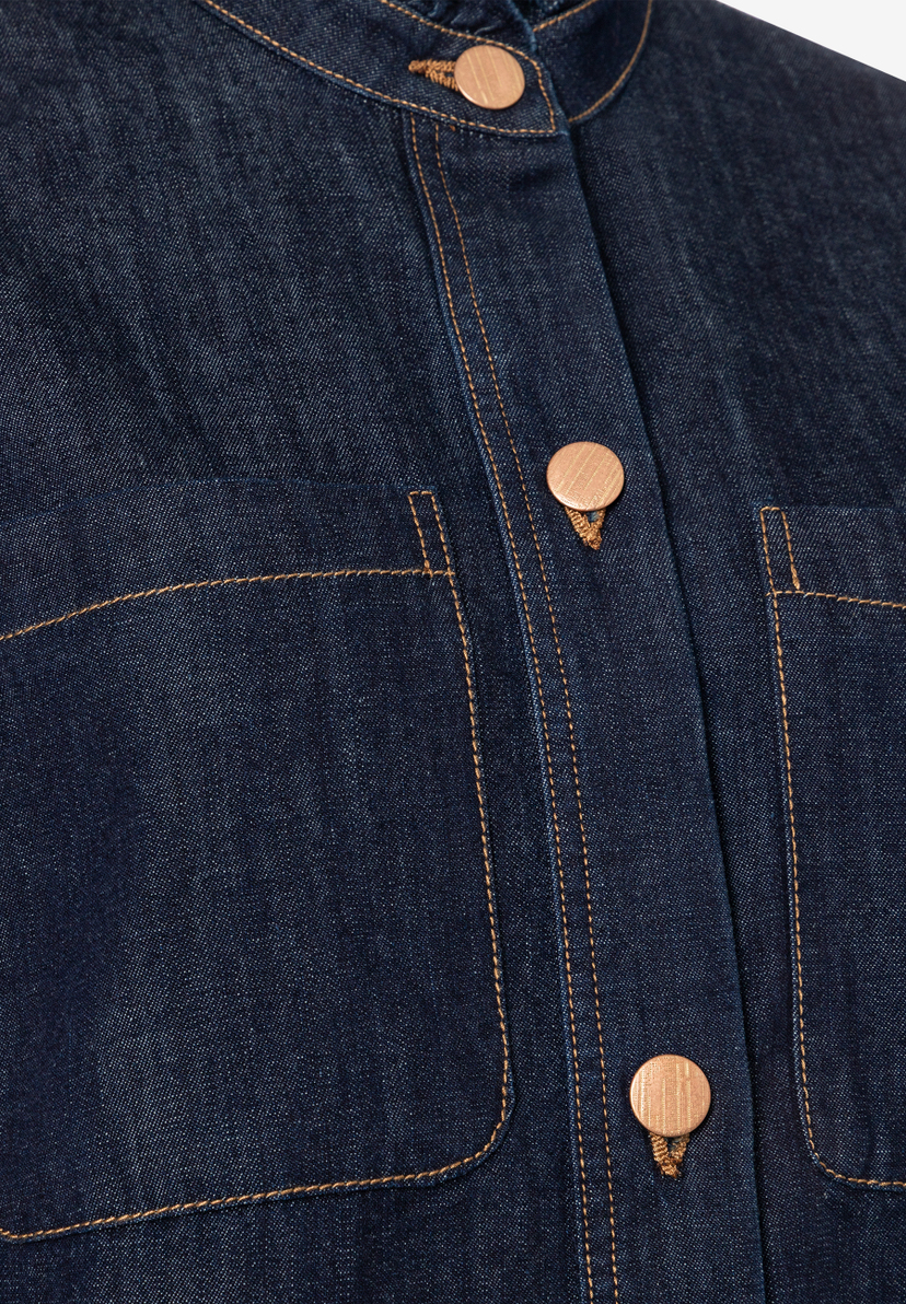 Nahaufnahme einer MORE & MORE Denim-Bluse mit Knöpfen und Taschen. Nahaufnahme einer MORE & MORE Denim-Bluse mit Knöpfen und Taschen.