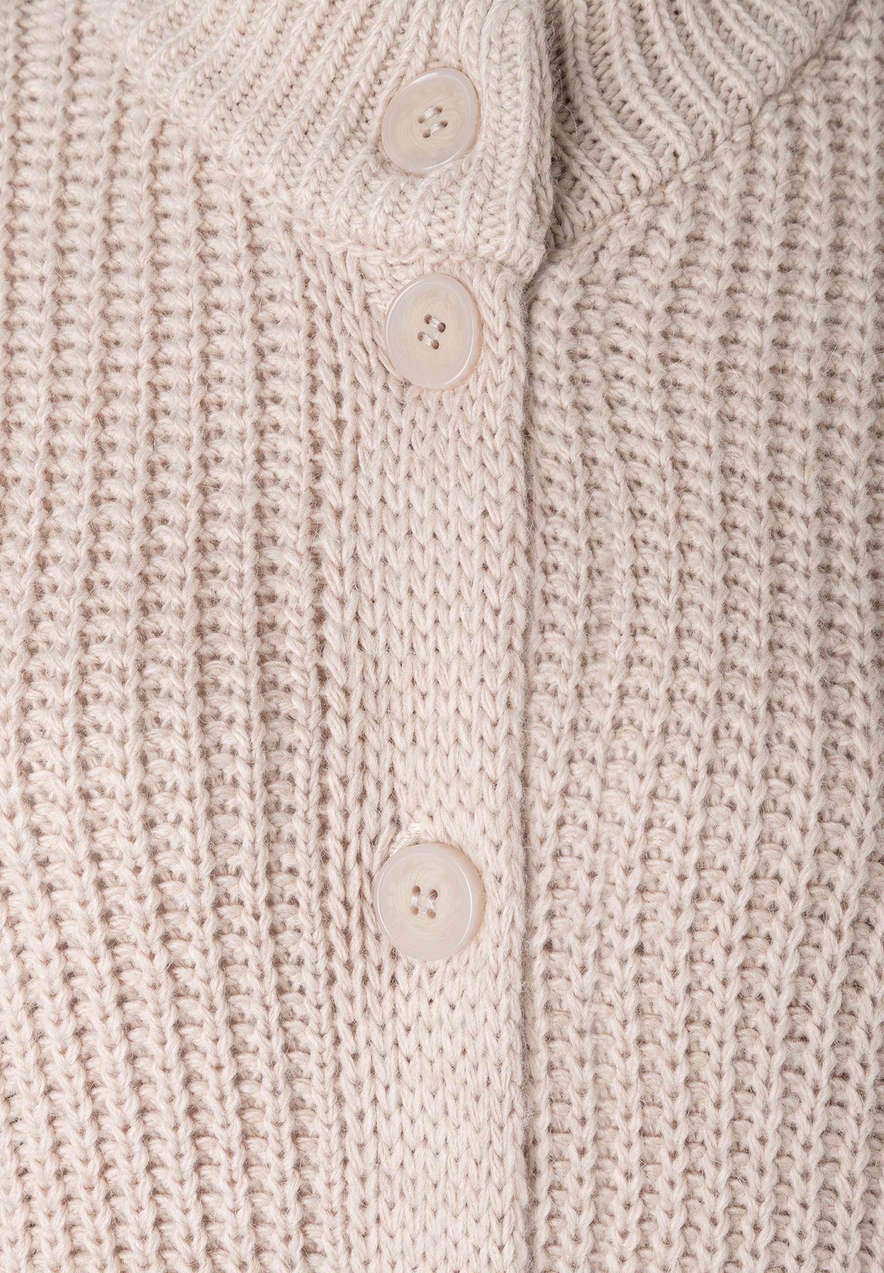 MORE & MORE Pullover: Detailansicht eines beigen, gerippten Strickpullovers mit drei cremefarbenen Knöpfen. MORE & MORE Pullover: Detailansicht eines beigen, gerippten Strickpullovers mit drei cremefarbenen Knöpfen.