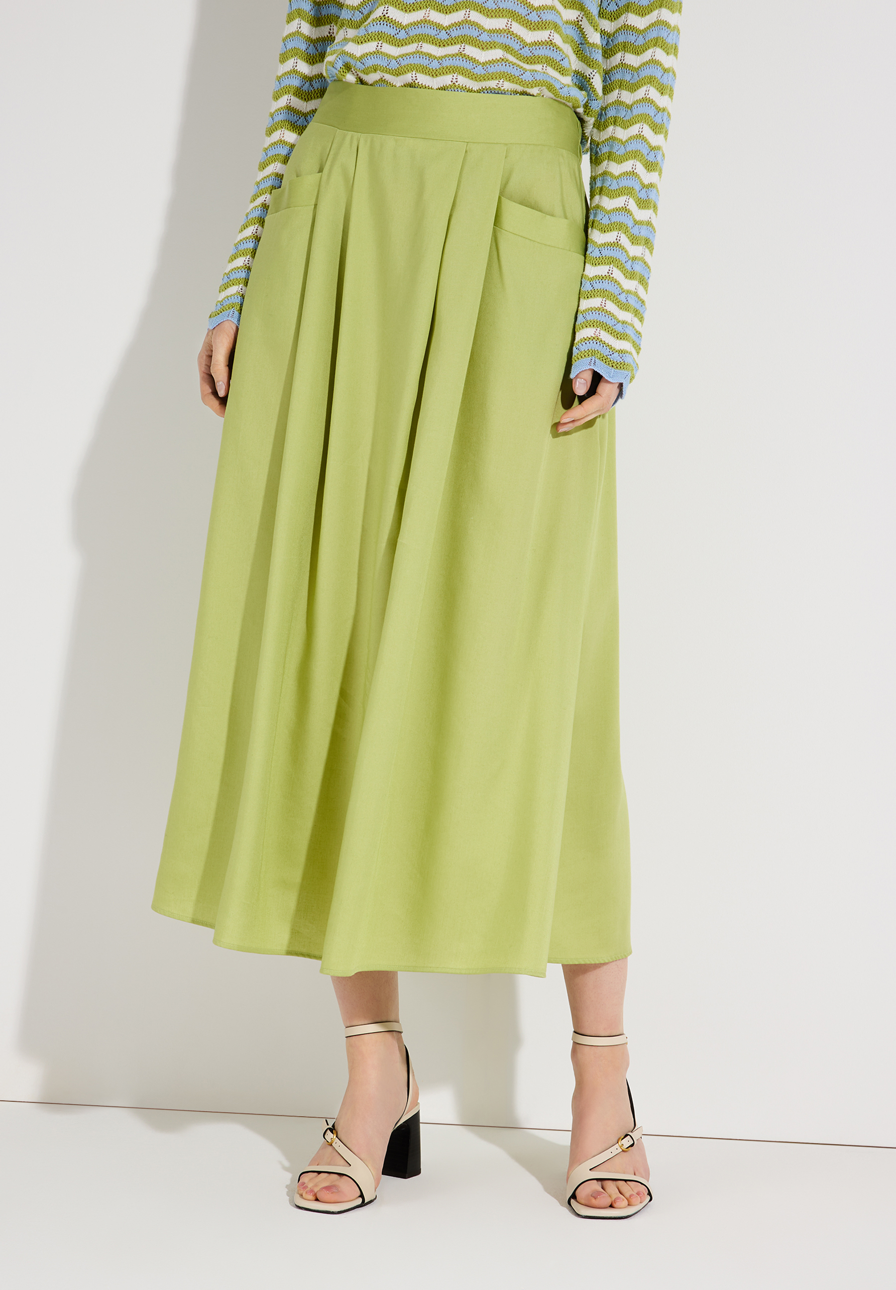 Ein hellgrüner Rock von MORE & MORE, kombiniert mit einem farbigen Oberteil und hellen Schuhen, vor einem weißen Hintergrund.
