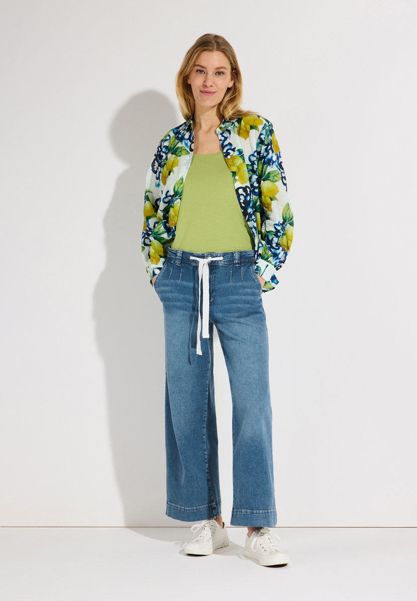 Eine Frau trägt MORE & MORE Jeans aus Denim mit weitem Bein und einen gestreiften Pullover. Eine Frau trägt MORE & MORE Jeans aus Denim mit weitem Bein und einen gestreiften Pullover.