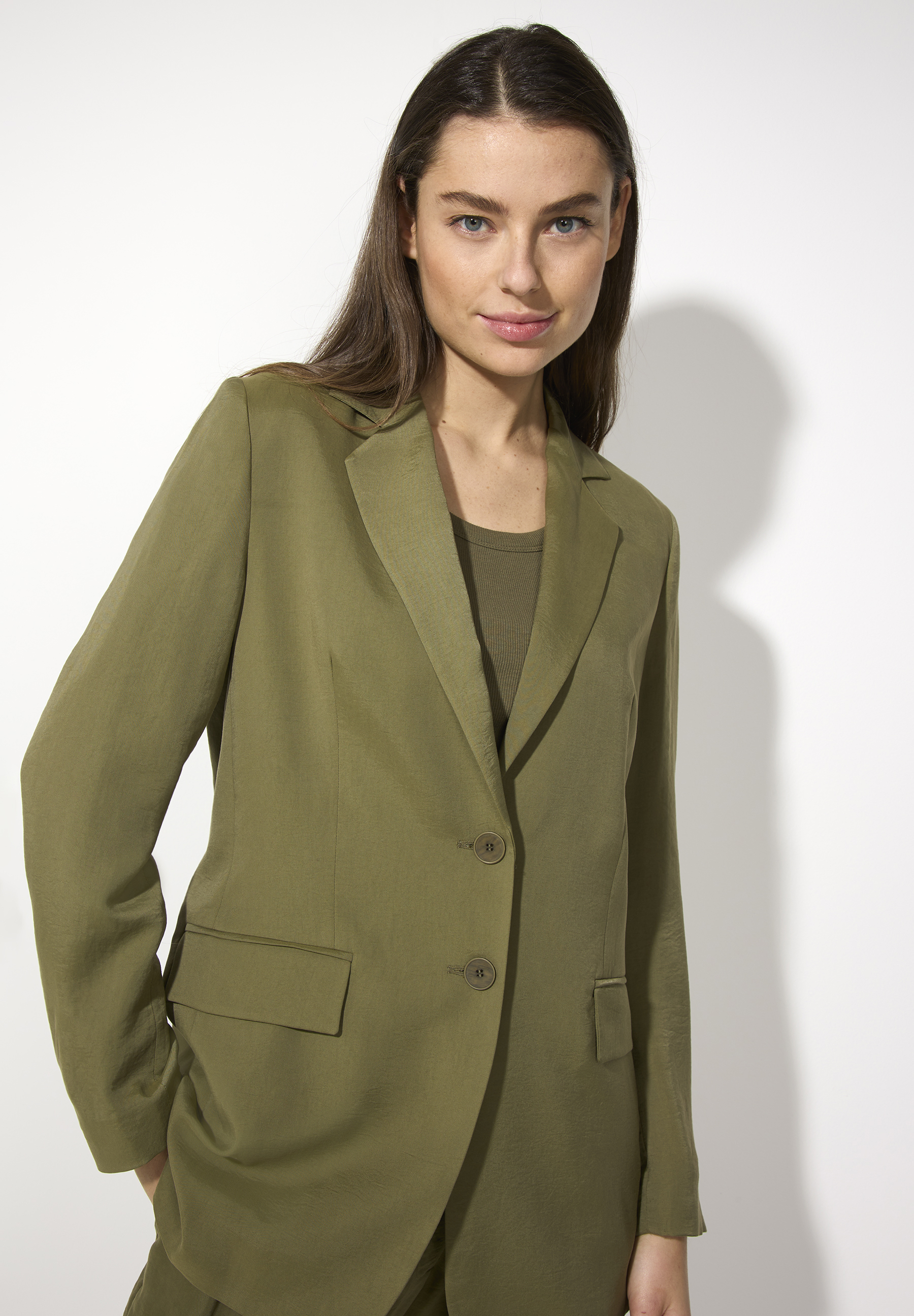 Eine Frau trägt einen olivgrünen Blazer von MORE & MORE. Der Blazer ist aus Webware und bietet einen angenehmen, elastischen Tragekomfort.