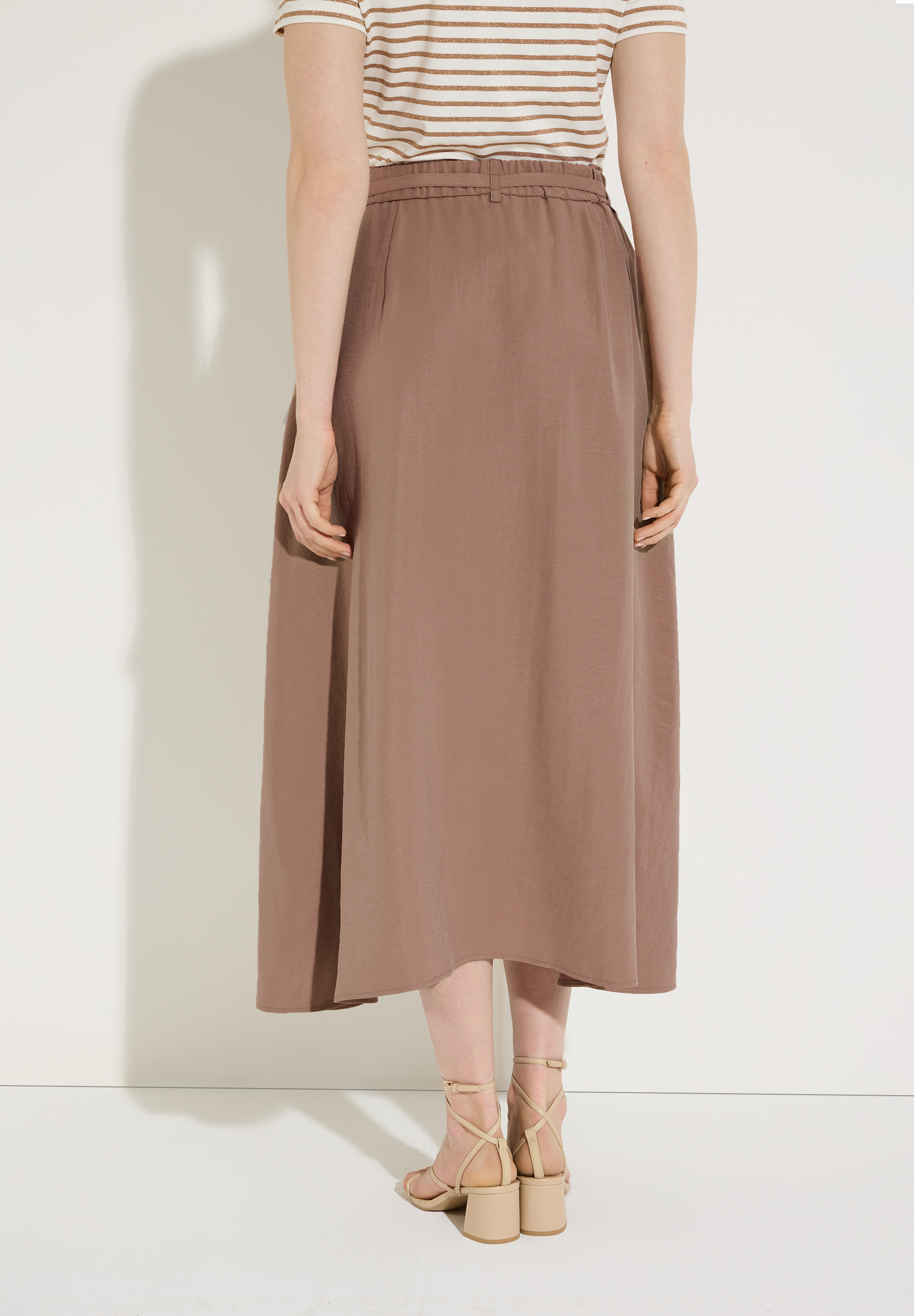 Die Rückansicht eines Models mit einem Rock der Marke MORE & MORE. Der Rock ist knöchellang und hat eine Webware-Konstruktion.