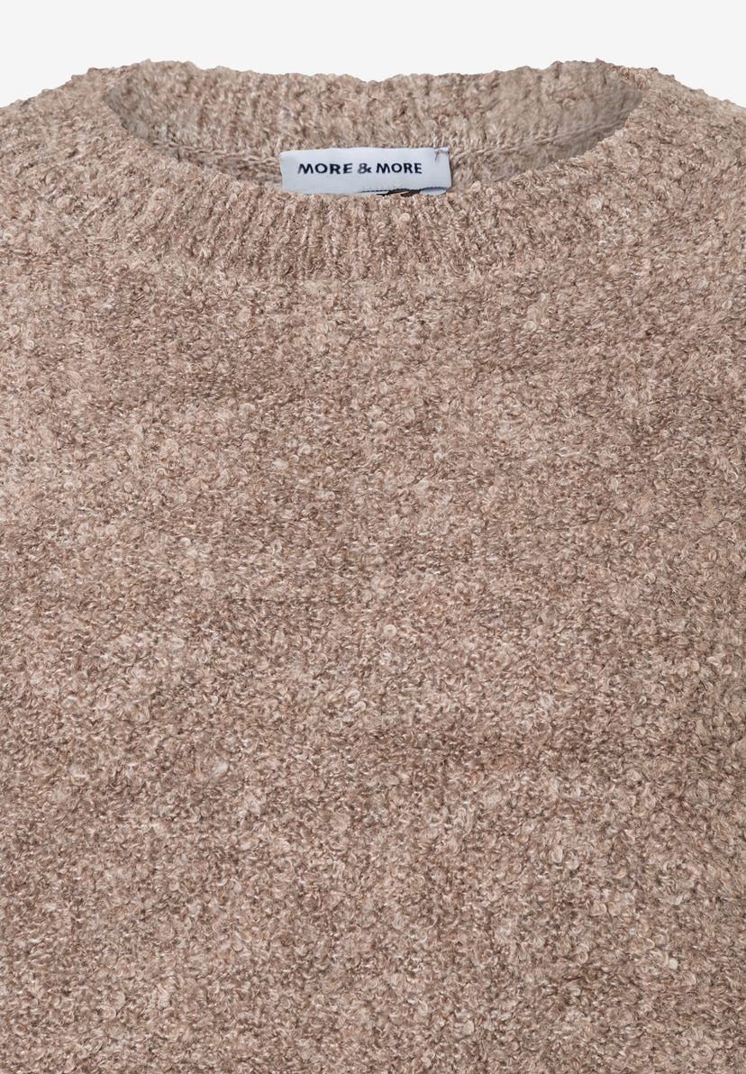 Nahaufnahme eines beigen Bouclé-Pullovers der Marke MORE & MORE, der warm und angenehm zu tragen ist. Nahaufnahme eines beigen Bouclé-Pullovers der Marke MORE & MORE, der warm und angenehm zu tragen ist.