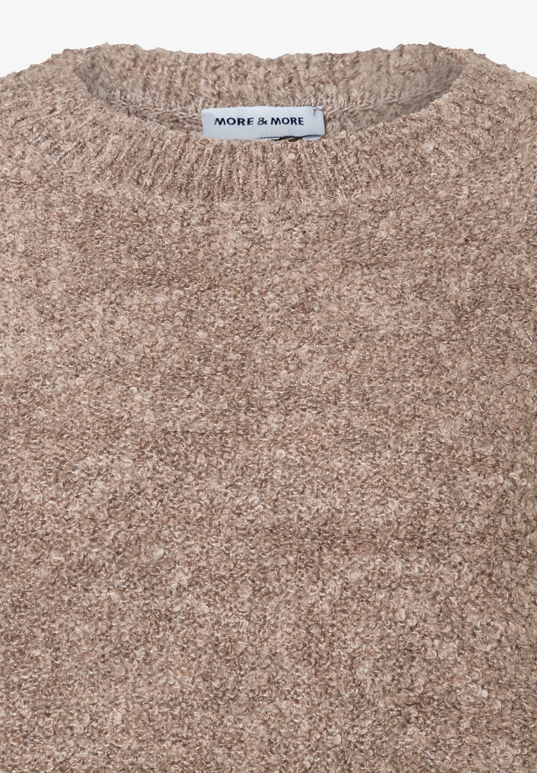 Nahaufnahme eines beigen Bouclé-Pullovers der Marke MORE & MORE, der warm und angenehm zu tragen ist. Nahaufnahme eines beigen Bouclé-Pullovers der Marke MORE & MORE, der warm und angenehm zu tragen ist.
