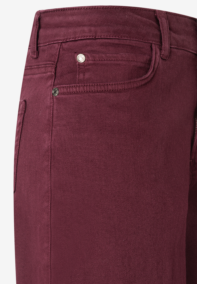 Detailaufnahme einer bordeauxroten MORE & MORE Jeanshose aus Denim mit elastischem, angenehmen Tragekomfort. Detailaufnahme einer bordeauxroten MORE & MORE Jeanshose aus Denim mit elastischem, angenehmen Tragekomfort.