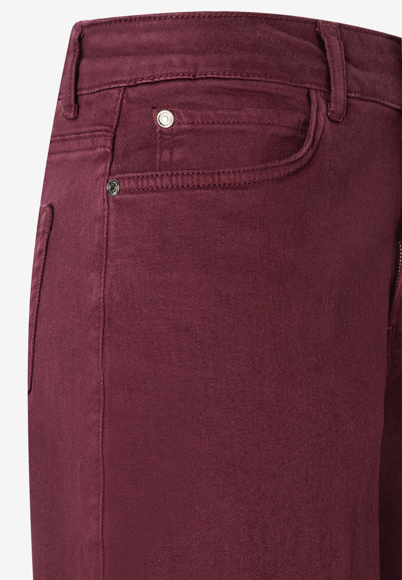 Detailaufnahme einer bordeauxroten MORE & MORE Jeanshose aus Denim mit elastischem, angenehmen Tragekomfort. Detailaufnahme einer bordeauxroten MORE & MORE Jeanshose aus Denim mit elastischem, angenehmen Tragekomfort.