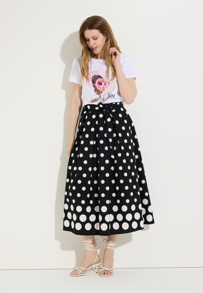Eine Frau trägt ein MORE & MORE T-Shirt mit Jersey-Material und einen schwarzen Rock mit weißen Punkten. Eine Frau trägt ein MORE & MORE T-Shirt mit Jersey-Material und einen schwarzen Rock mit weißen Punkten.
