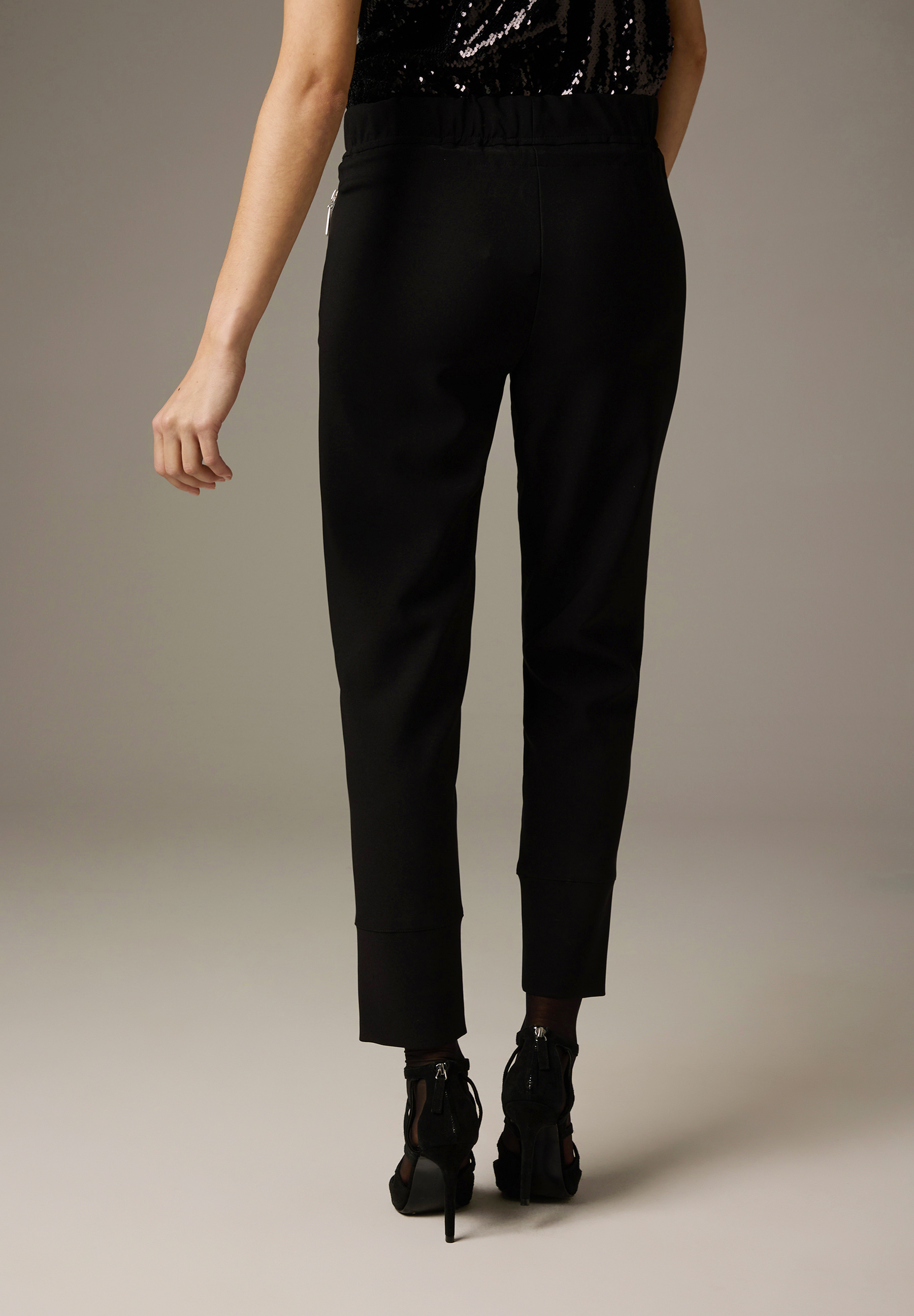 Die Rückansicht einer Frau mit schwarzen MORE & MORE Hosen/Jeans und schwarzen High Heels. Die Rückansicht einer Frau mit schwarzen MORE & MORE Hosen/Jeans und schwarzen High Heels.