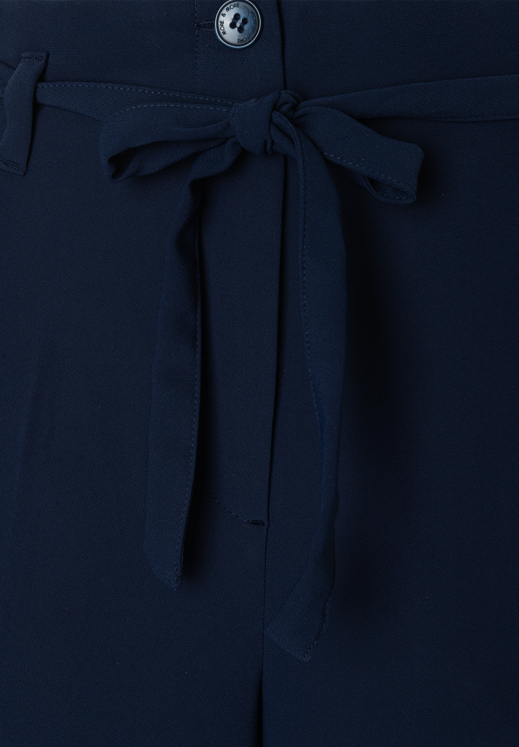Nahaufnahme einer marineblauen MORE & MORE Hose/Jeans mit fließendem, angenehmem Webware-Material und einem dekorativen Schleifengürtel. Nahaufnahme einer marineblauen MORE & MORE Hose/Jeans mit fließendem, angenehmem Webware-Material und einem dekorativen Schleifengürtel.