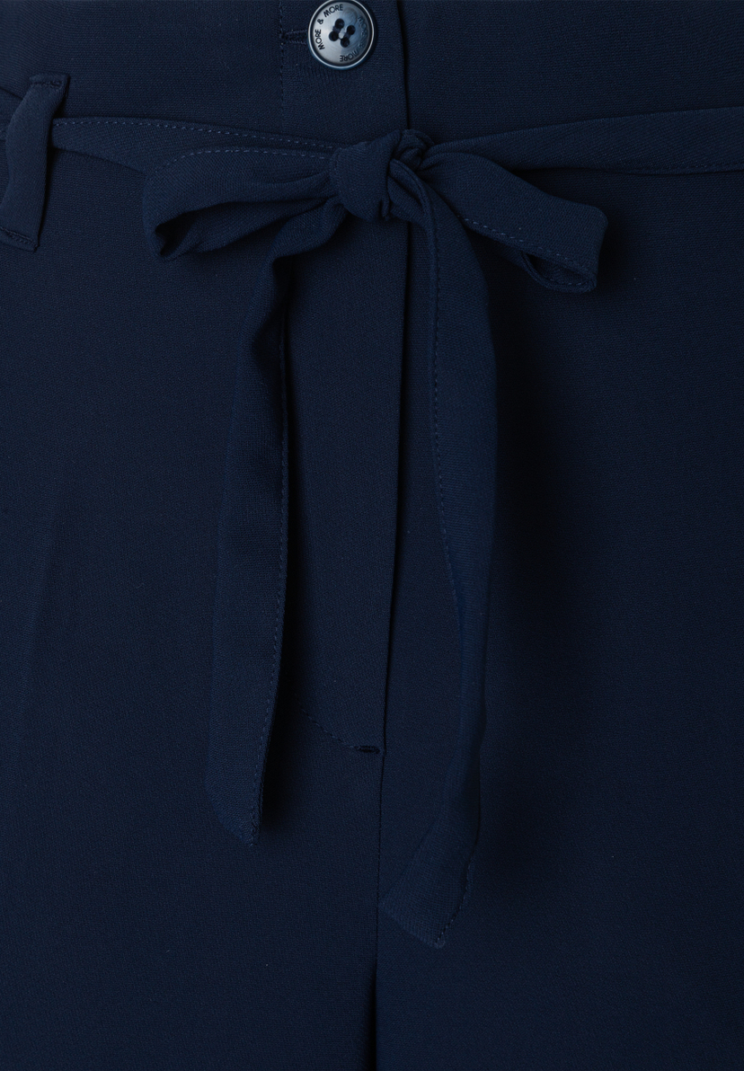 Nahaufnahme einer marineblauen MORE & MORE Hose/Jeans mit fließendem, angenehmem Webware-Material und einem dekorativen Schleifengürtel. Nahaufnahme einer marineblauen MORE & MORE Hose/Jeans mit fließendem, angenehmem Webware-Material und einem dekorativen Schleifengürtel.