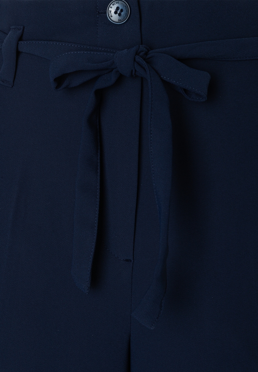 Nahaufnahme einer marineblauen MORE & MORE Hose/Jeans mit fließendem, angenehmem Webware-Material und einem dekorativen Schleifengürtel. Nahaufnahme einer marineblauen MORE & MORE Hose/Jeans mit fließendem, angenehmem Webware-Material und einem dekorativen Schleifengürtel.