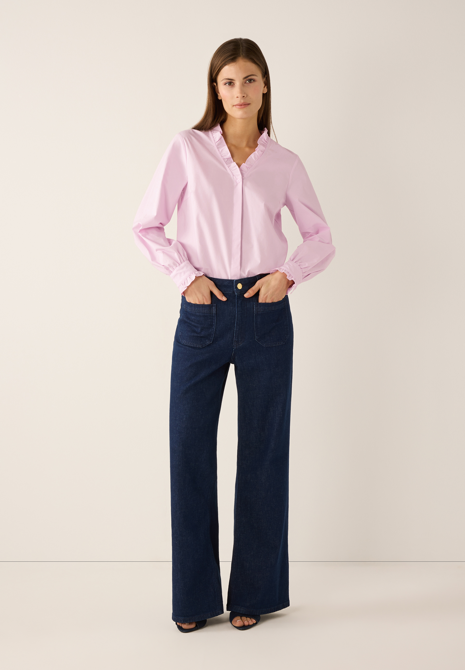 Eine Frau in MORE & MORE Bluse aus Popeline und Jeans mit Händen in den Taschen. Eine Frau in MORE & MORE Bluse aus Popeline und Jeans mit Händen in den Taschen.