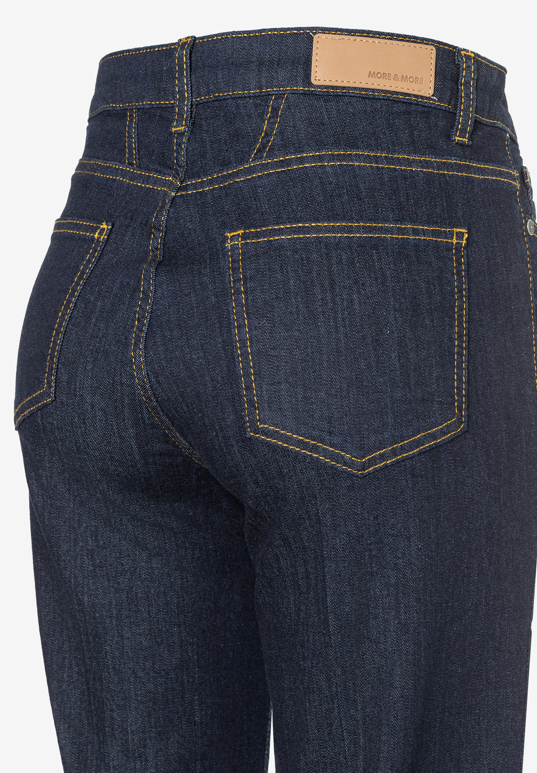 Nahaufnahme der Rückseite einer MORE & MORE Jeans aus Denim mit gelben Nähten. Nahaufnahme der Rückseite einer MORE & MORE Jeans aus Denim mit gelben Nähten.