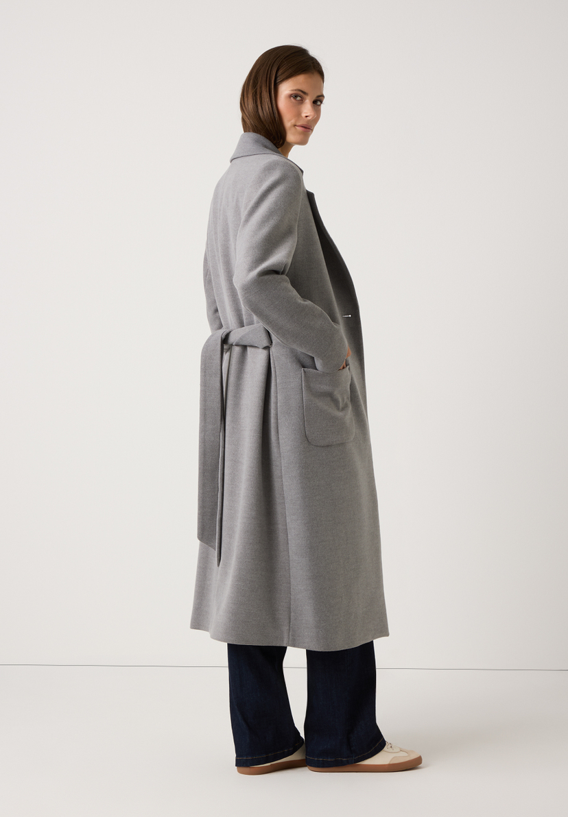 Eine Frau trägt einen grauen MORE & MORE Mantel aus Webware mit Gürtel. Angenehmer Tragekomfort. Eine Frau trägt einen grauen MORE & MORE Mantel aus Webware mit Gürtel. Angenehmer Tragekomfort.