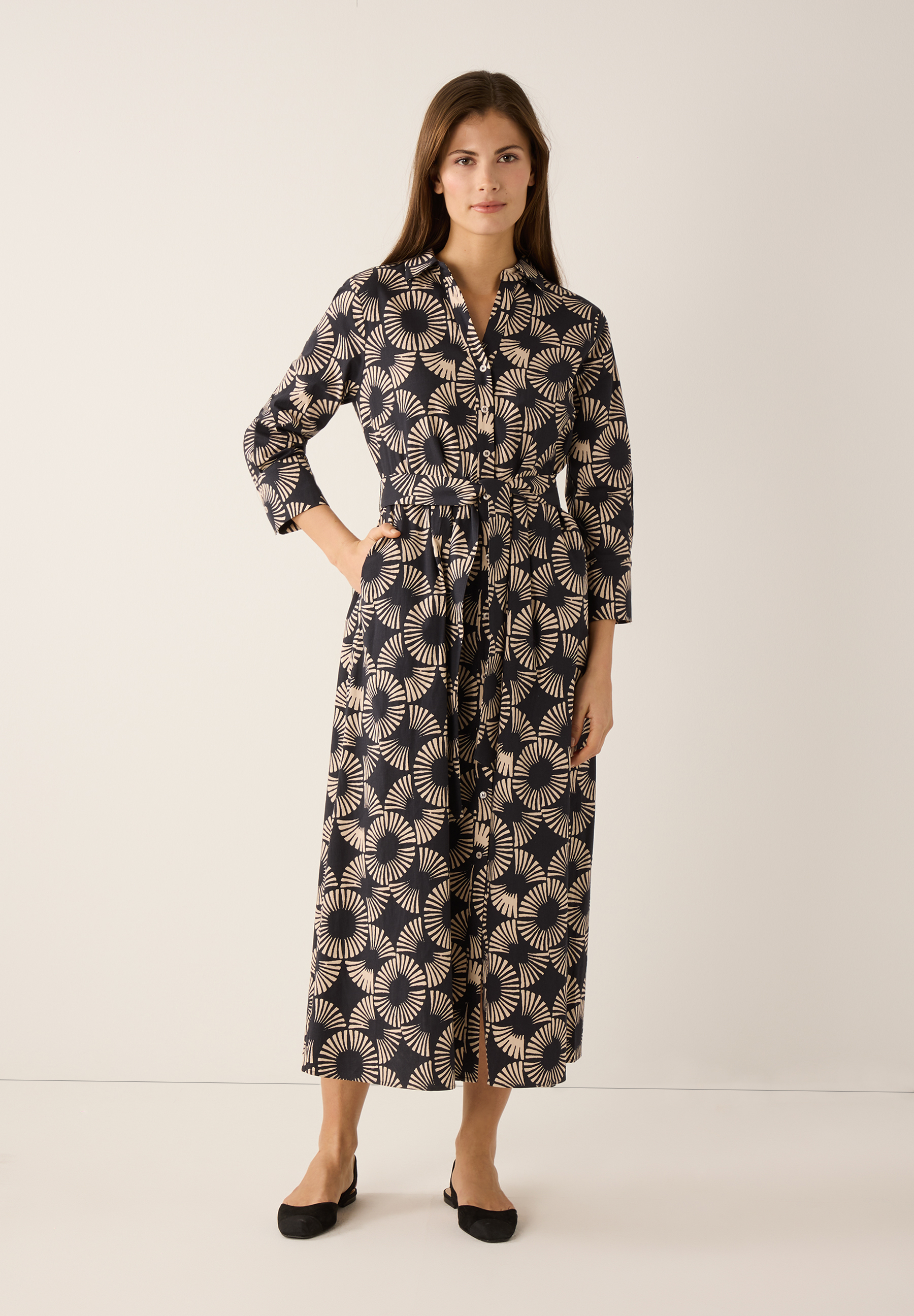 Eine Frau trägt ein MORE & MORE Popeline-Oberteil mit Stretch und grafischem Muster. Es ist ein bequemes, elegantes Kleid. Eine Frau trägt ein MORE & MORE Popeline-Oberteil mit Stretch und grafischem Muster. Es ist ein bequemes, elegantes Kleid.