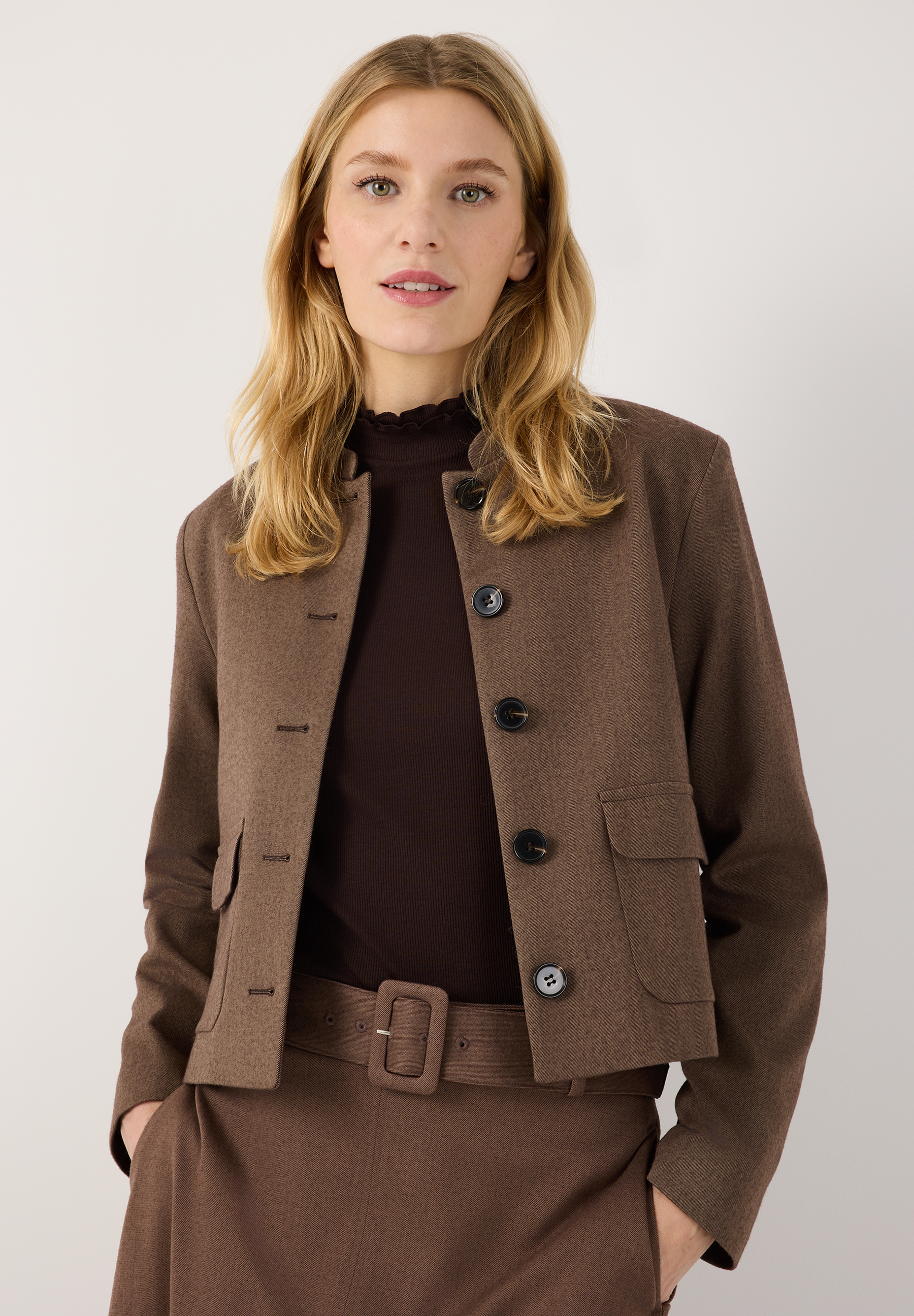 MORE & MORE Blazer in Braun, vorne geknöpft, mit Taschen, kombiniert mit braunem Rollkragenpullover und Hose.