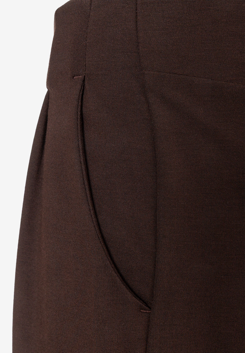 MORE & MORE dunkelbraune Stoffhose mit seitlicher Eingrifftasche, Nahaufnahme auf braunem Stoff. MORE & MORE dunkelbraune Stoffhose mit seitlicher Eingrifftasche, Nahaufnahme auf braunem Stoff.