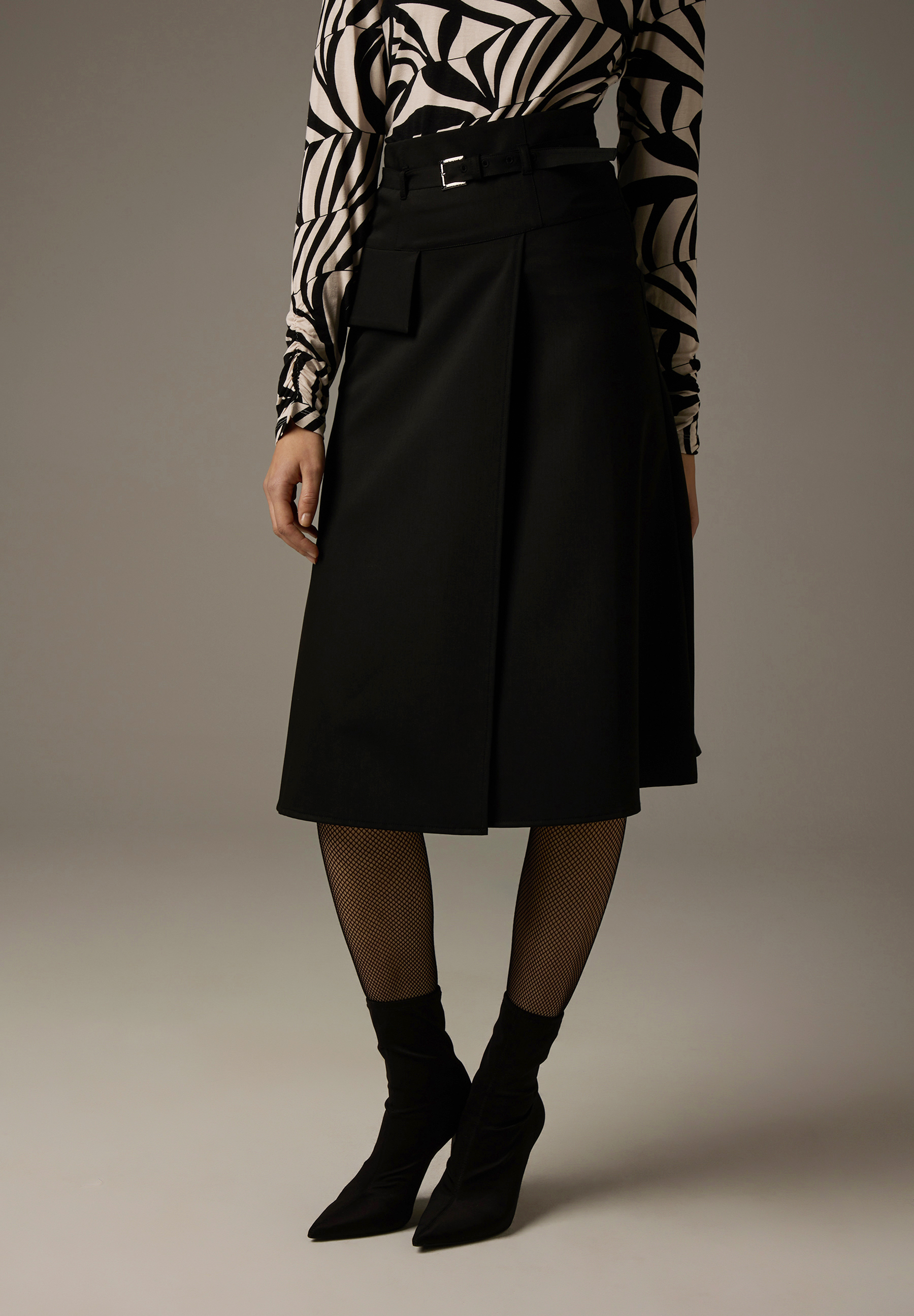 Ein Rock von MORE & MORE in Schwarz mit einem Print-Oberteil und schwarzen Stiefeletten. Ein Rock von MORE & MORE in Schwarz mit einem Print-Oberteil und schwarzen Stiefeletten.