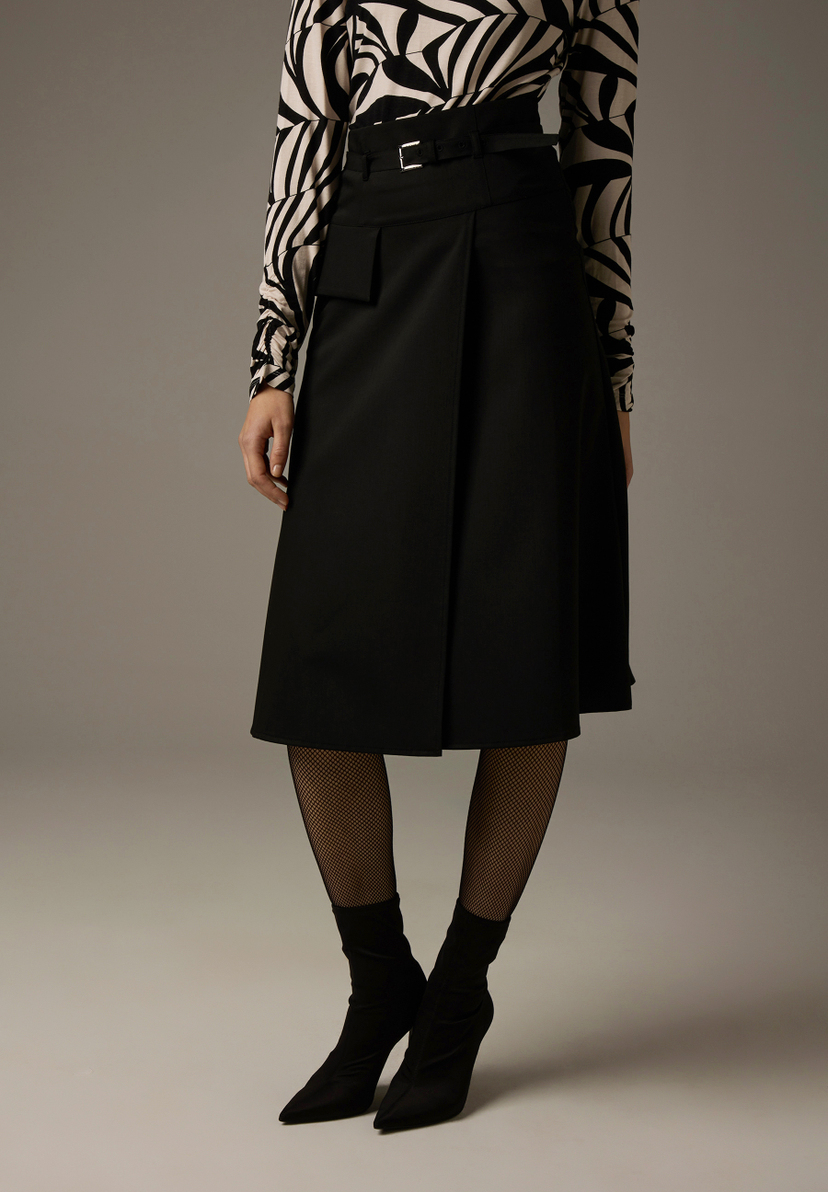 Ein Rock von MORE & MORE in Schwarz mit einem Print-Oberteil und schwarzen Stiefeletten. Ein Rock von MORE & MORE in Schwarz mit einem Print-Oberteil und schwarzen Stiefeletten.