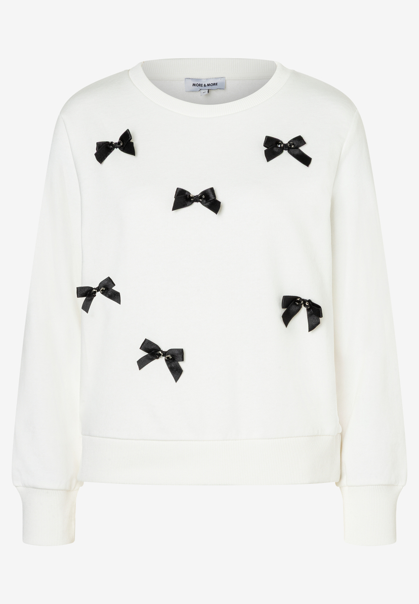 Ein Sweatshirt von MORE & MORE in Weiß mit schwarzen Schleifen. Ein Sweatshirt von MORE & MORE in Weiß mit schwarzen Schleifen.