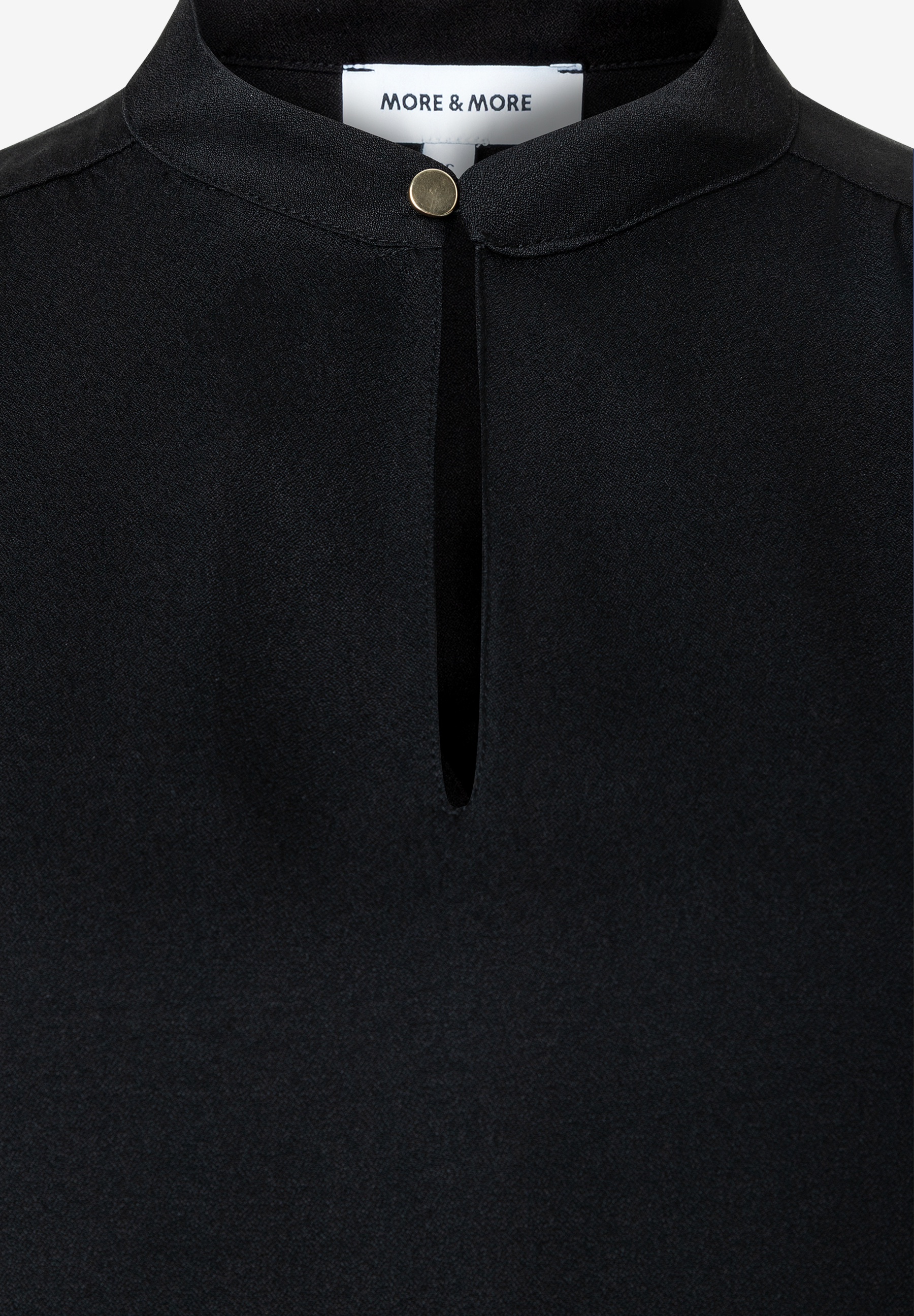 MORE & MORE schwarze Bluse mit Stehkragen und Schlüssellochausschnitt mit goldfarbenem Knopf auf weißem Hintergrund. MORE & MORE schwarze Bluse mit Stehkragen und Schlüssellochausschnitt mit goldfarbenem Knopf auf weißem Hintergrund.