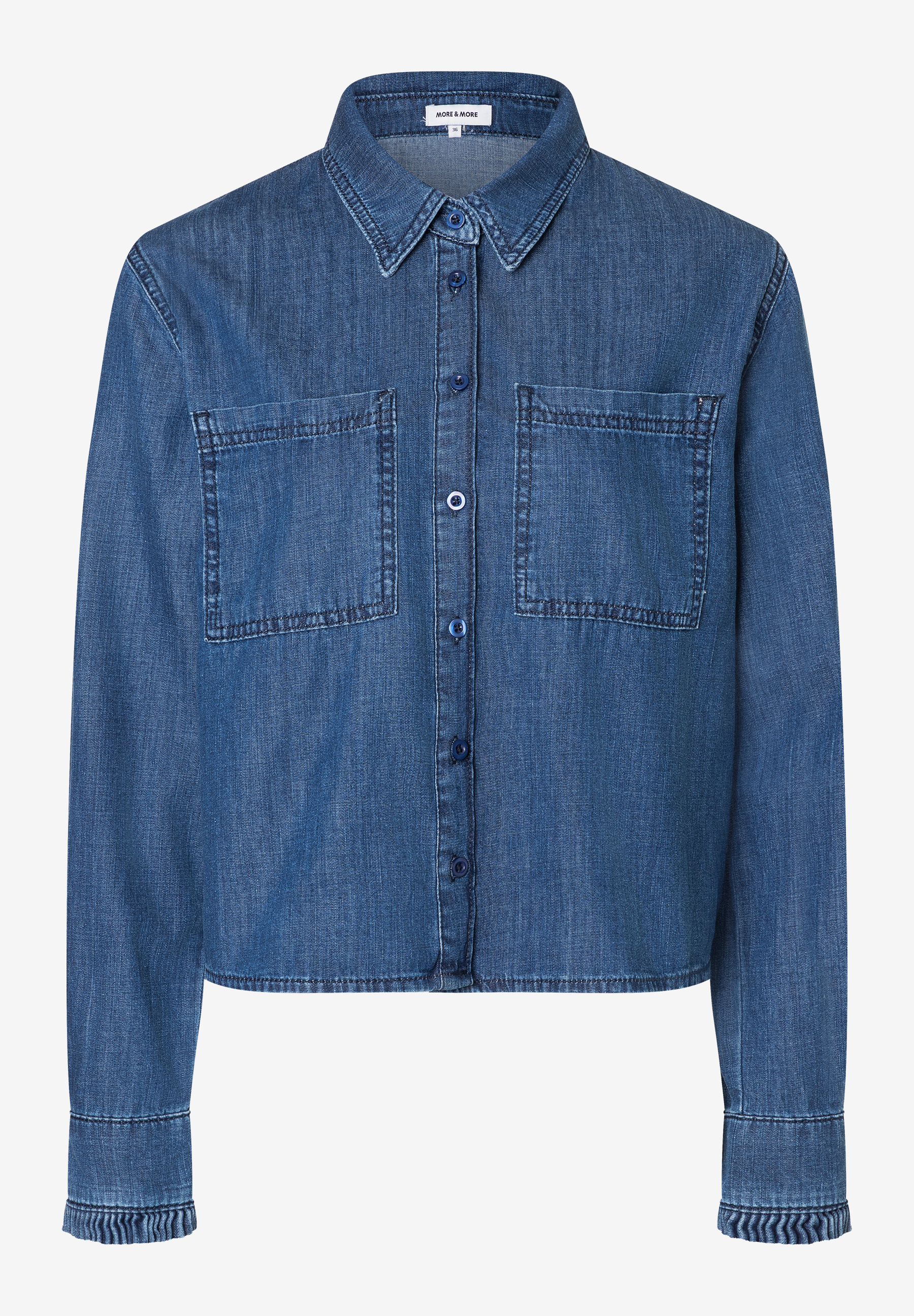 Eine MORE & MORE Damenbluse aus Denim mit Knopfleiste und zwei Brusttaschen. Eine MORE & MORE Damenbluse aus Denim mit Knopfleiste und zwei Brusttaschen.