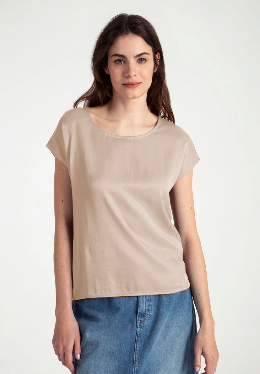 Eine Frau trägt ein MORE & MORE-Top aus Materialmix mit seidigem Glanz und Jersey, kombiniert mit einem Jeansrock. Eine Frau trägt ein MORE & MORE-Top aus Materialmix mit seidigem Glanz und Jersey, kombiniert mit einem Jeansrock.