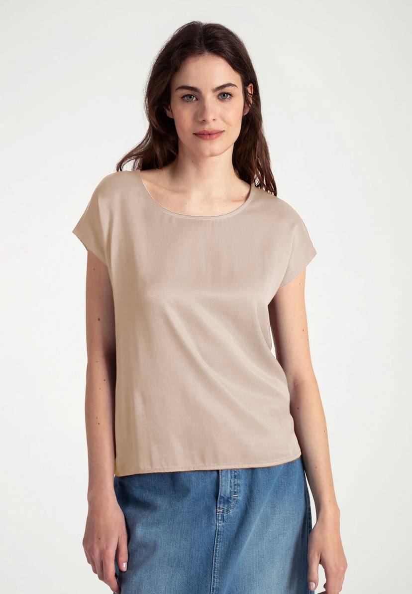 Eine Frau trägt ein MORE & MORE-Top aus Materialmix mit seidigem Glanz und Jersey, kombiniert mit einem Jeansrock. Eine Frau trägt ein MORE & MORE-Top aus Materialmix mit seidigem Glanz und Jersey, kombiniert mit einem Jeansrock.