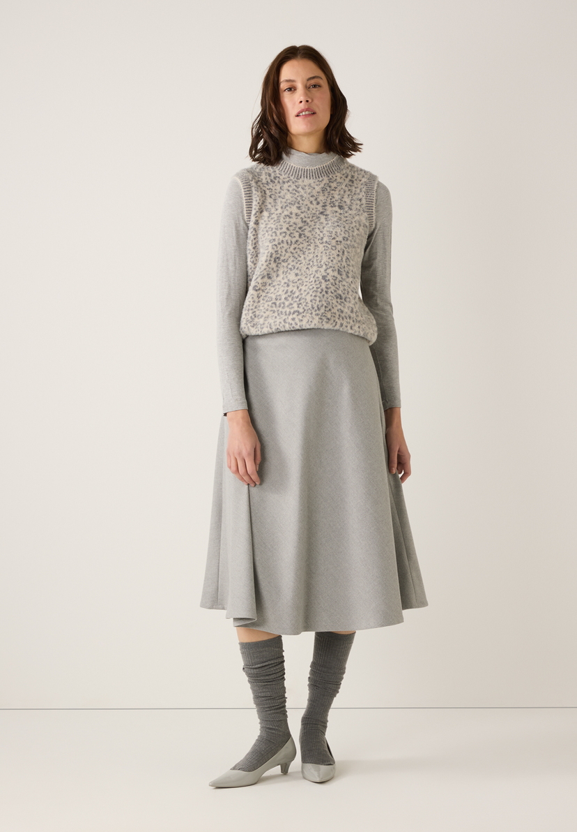 Eine Frau in MORE & MORE Kleidung: Rock, Top, Strümpfe und Schuhe in Grautönen. Eine Frau in MORE & MORE Kleidung: Rock, Top, Strümpfe und Schuhe in Grautönen.