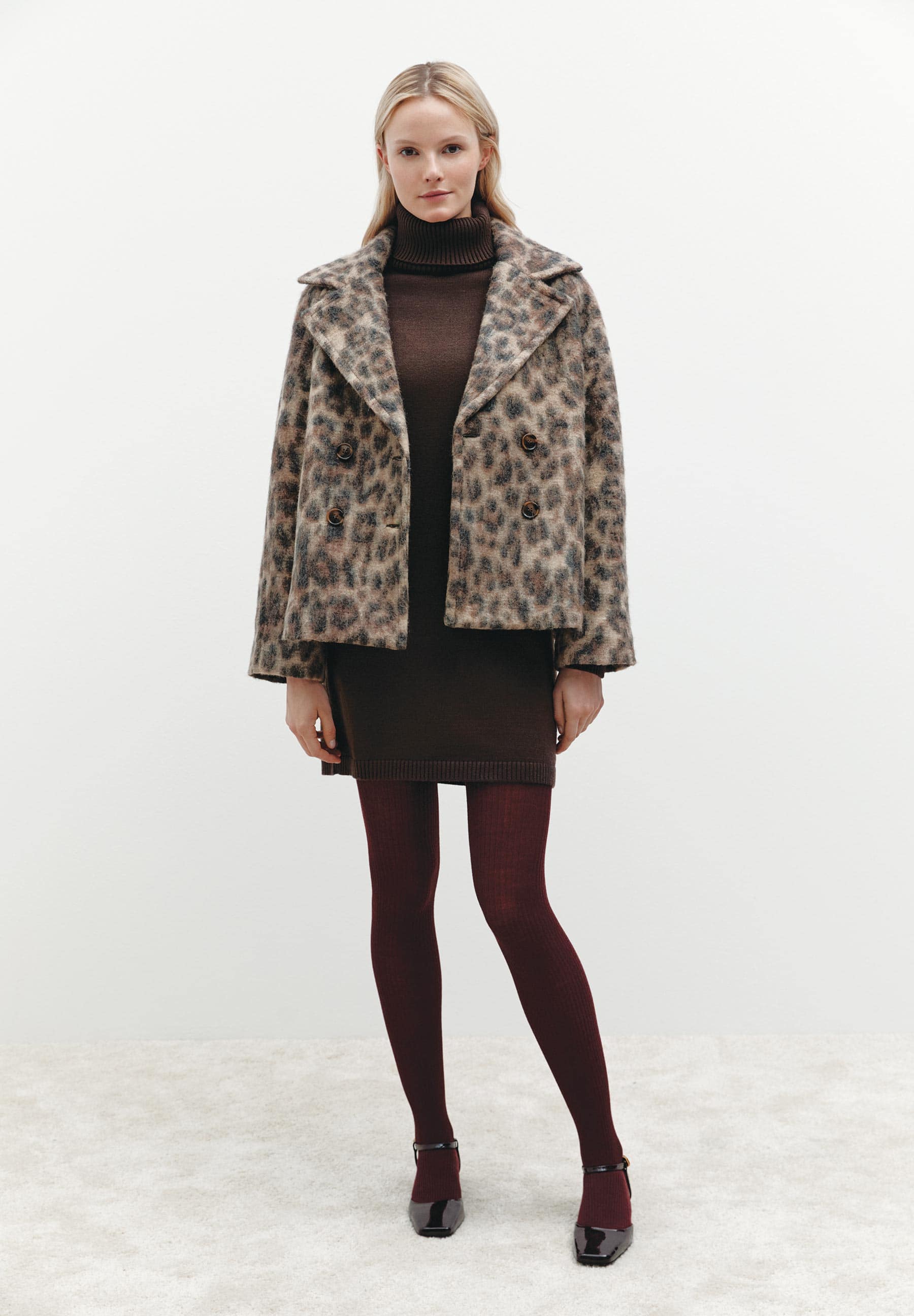 Eine Frau trägt ein MORE & MORE-Outfit mit Leopardenjacke, Rollkragenkleid und bordeauxroten Strumpfhosen. Eine Frau trägt ein MORE & MORE-Outfit mit Leopardenjacke, Rollkragenkleid und bordeauxroten Strumpfhosen.
