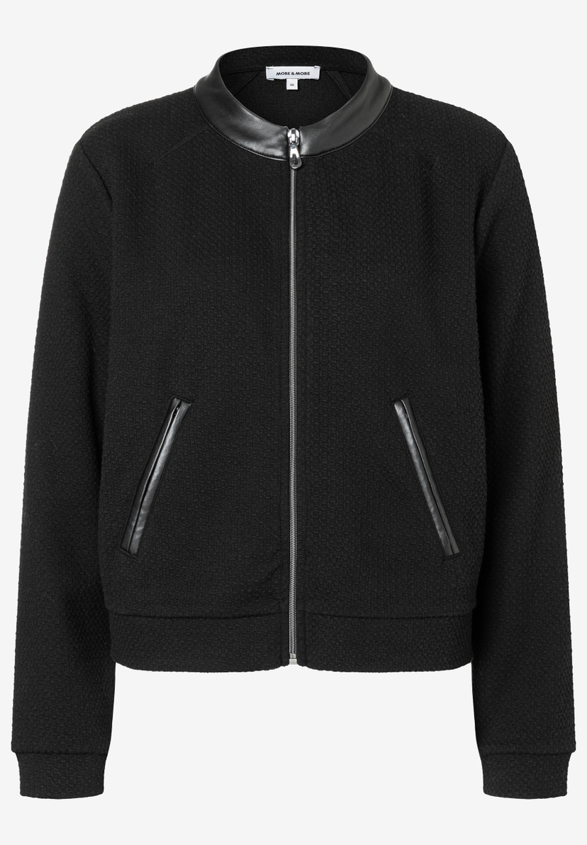 Ein schwarzes Oberteil von MORE & MORE, mit Kunstleder-Details, einer Textilstruktur und einem Reißverschluss vorne. Ein schwarzes Oberteil von MORE & MORE, mit Kunstleder-Details, einer Textilstruktur und einem Reißverschluss vorne.