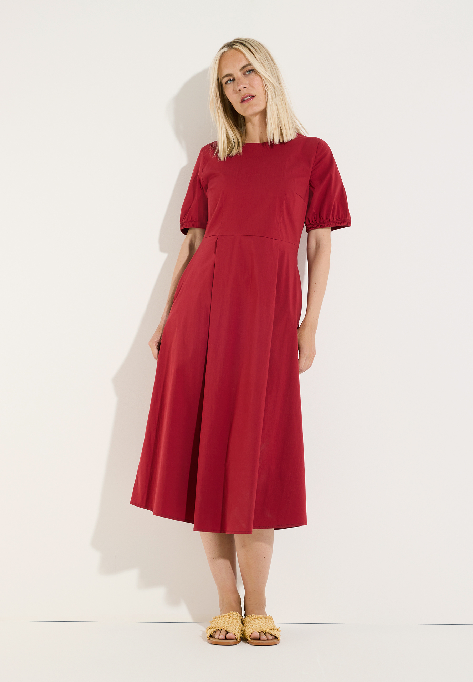 MORE & MORE Damen-Kleid in Rot. Eine schlanke, blonde Frau mit dem Kleid steht vor einer weißen Wand und blickt zur Kamera.