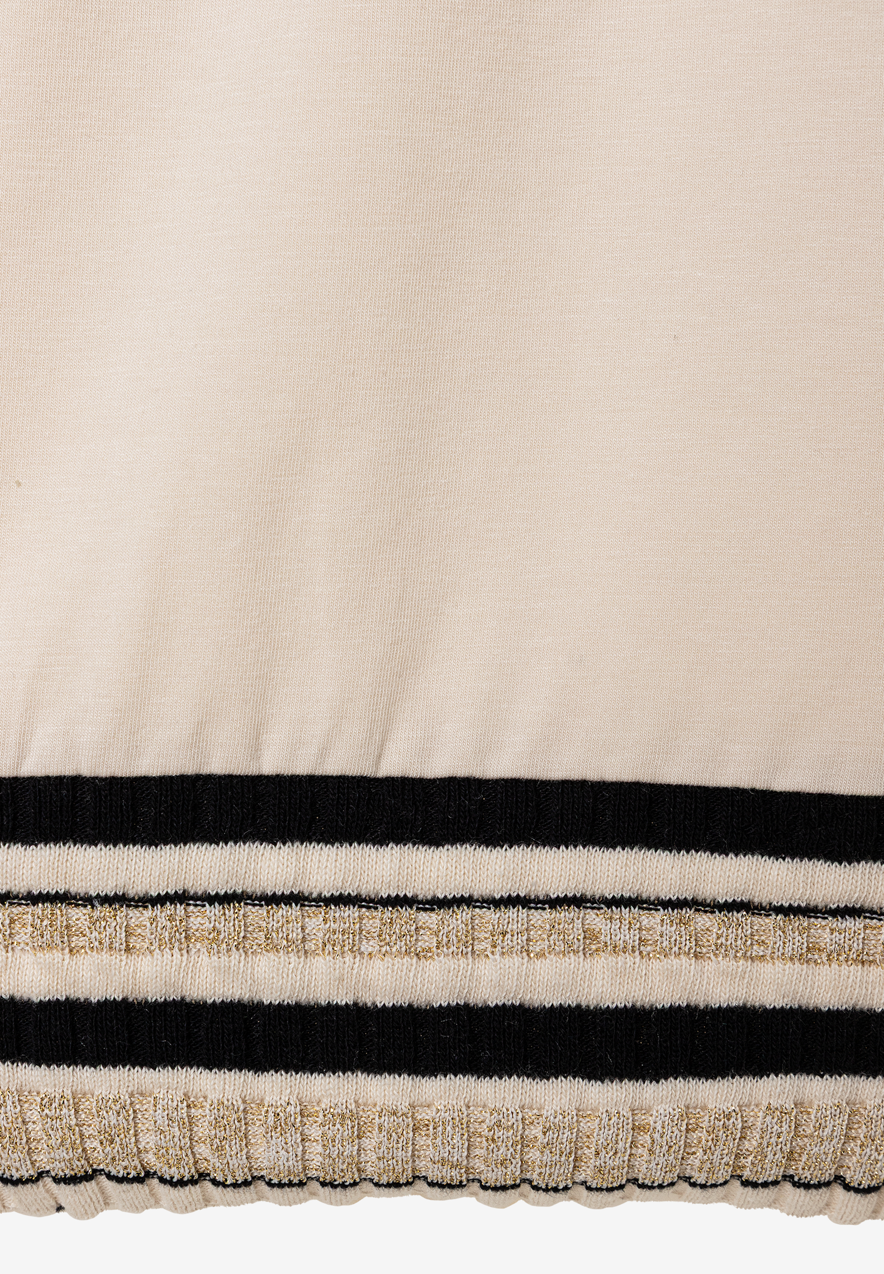 Nahaufnahme eines MORE & MORE Oberteils mit Jersey-Material. Es hat schwarzen, weißen und goldenen Streifen am unteren Rand. Nahaufnahme eines MORE & MORE Oberteils mit Jersey-Material. Es hat schwarzen, weißen und goldenen Streifen am unteren Rand.